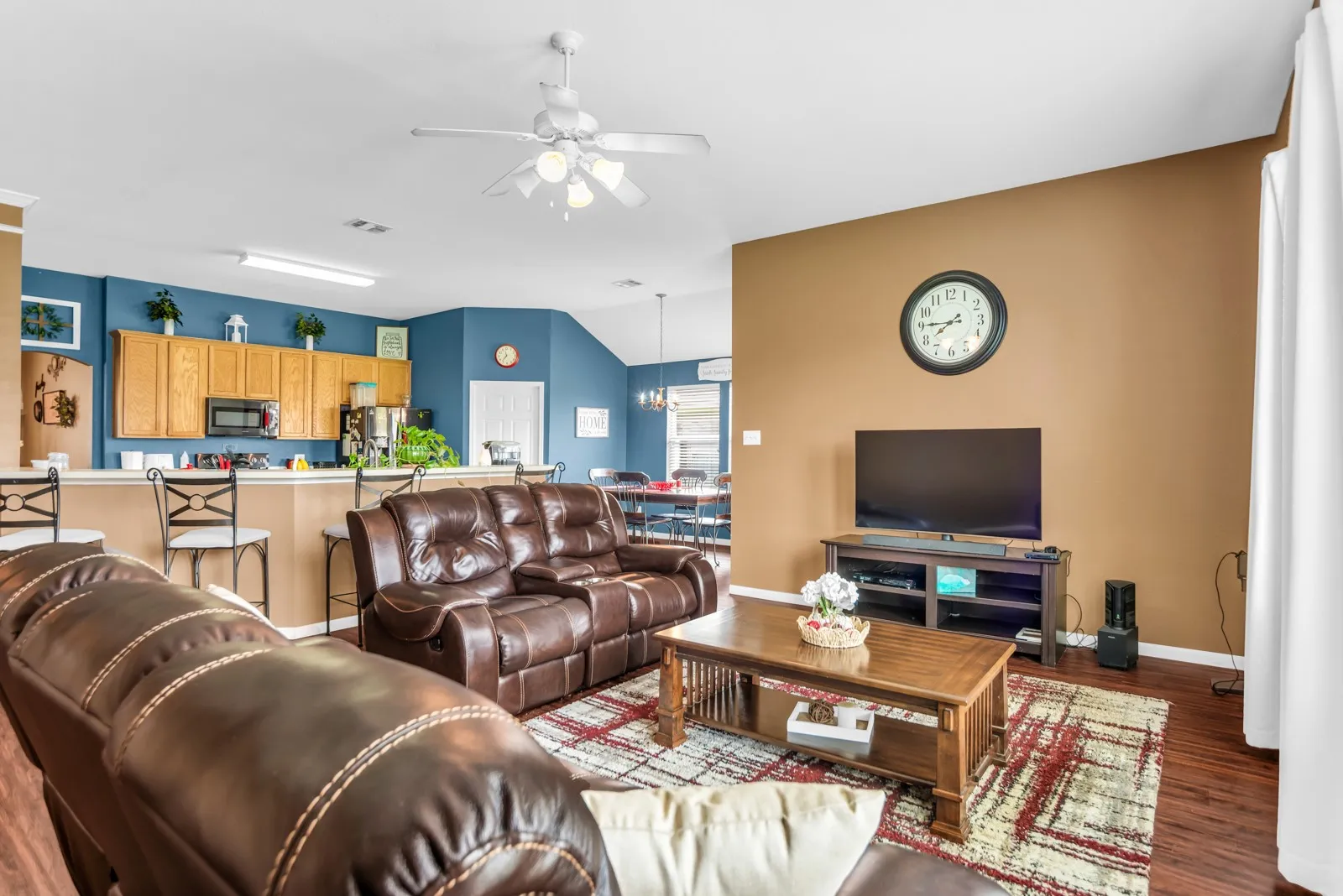 Open-concept living space featuring wood-finish flooring, a breakfast bar, and vaulted ceilings