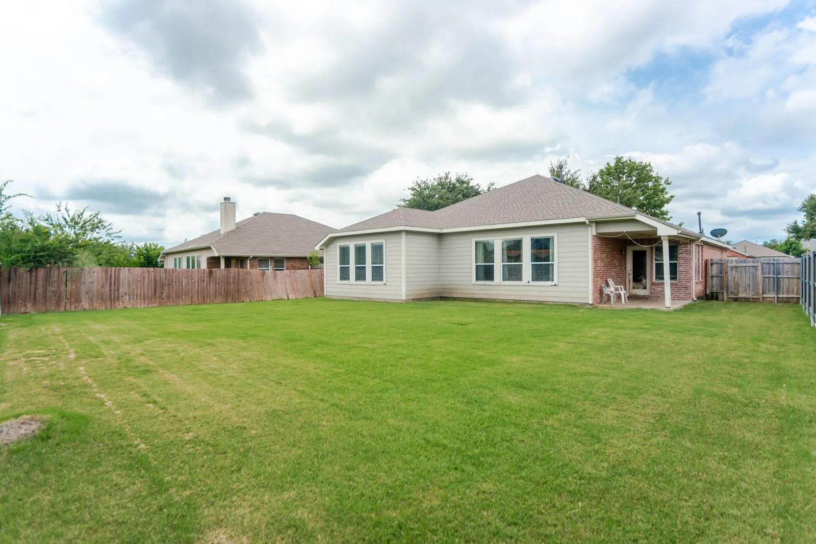 Expansive green lawn with a wood fence bordering the property
