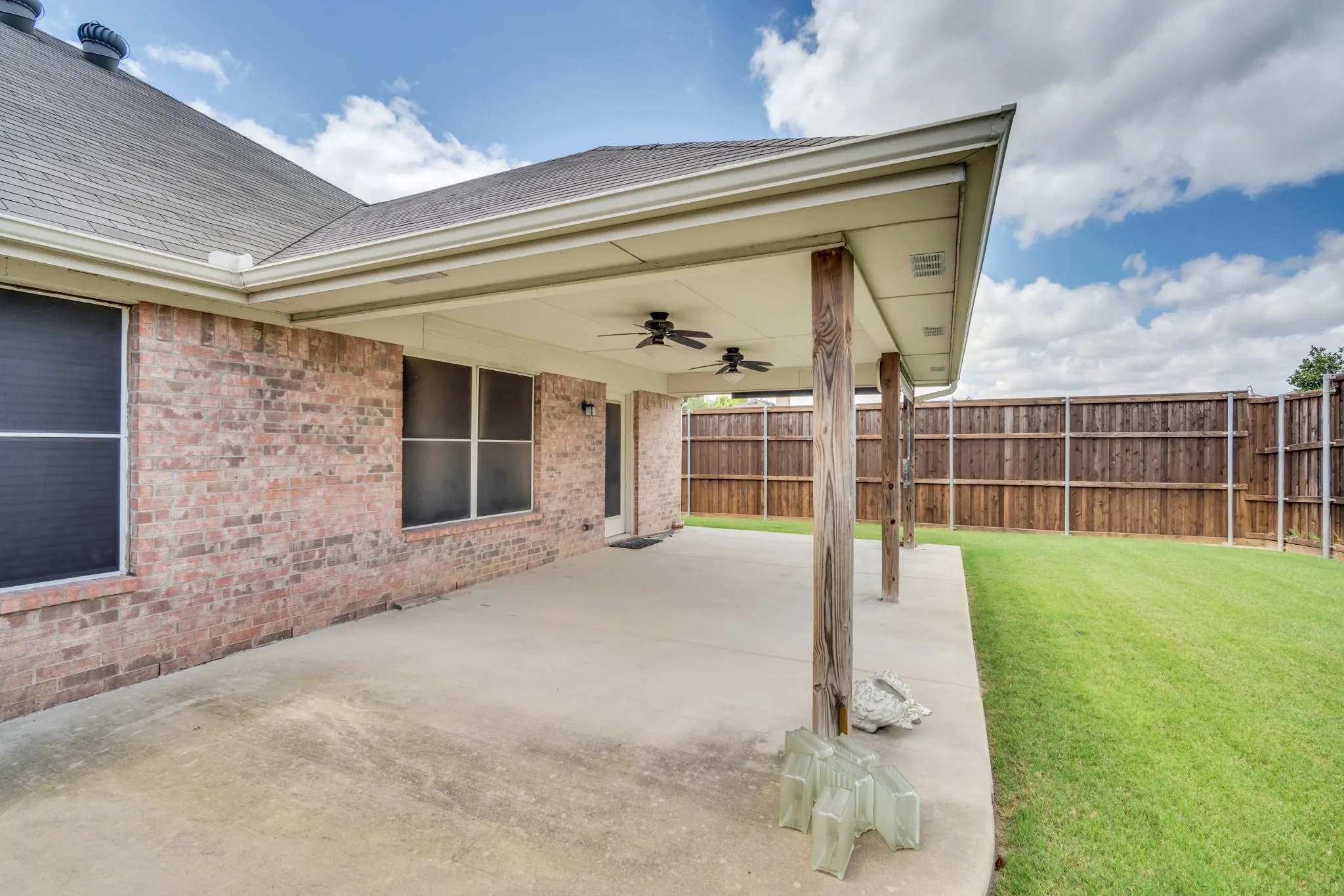 Expansive covered patio featuring sun screen shades and two ceiling fans
