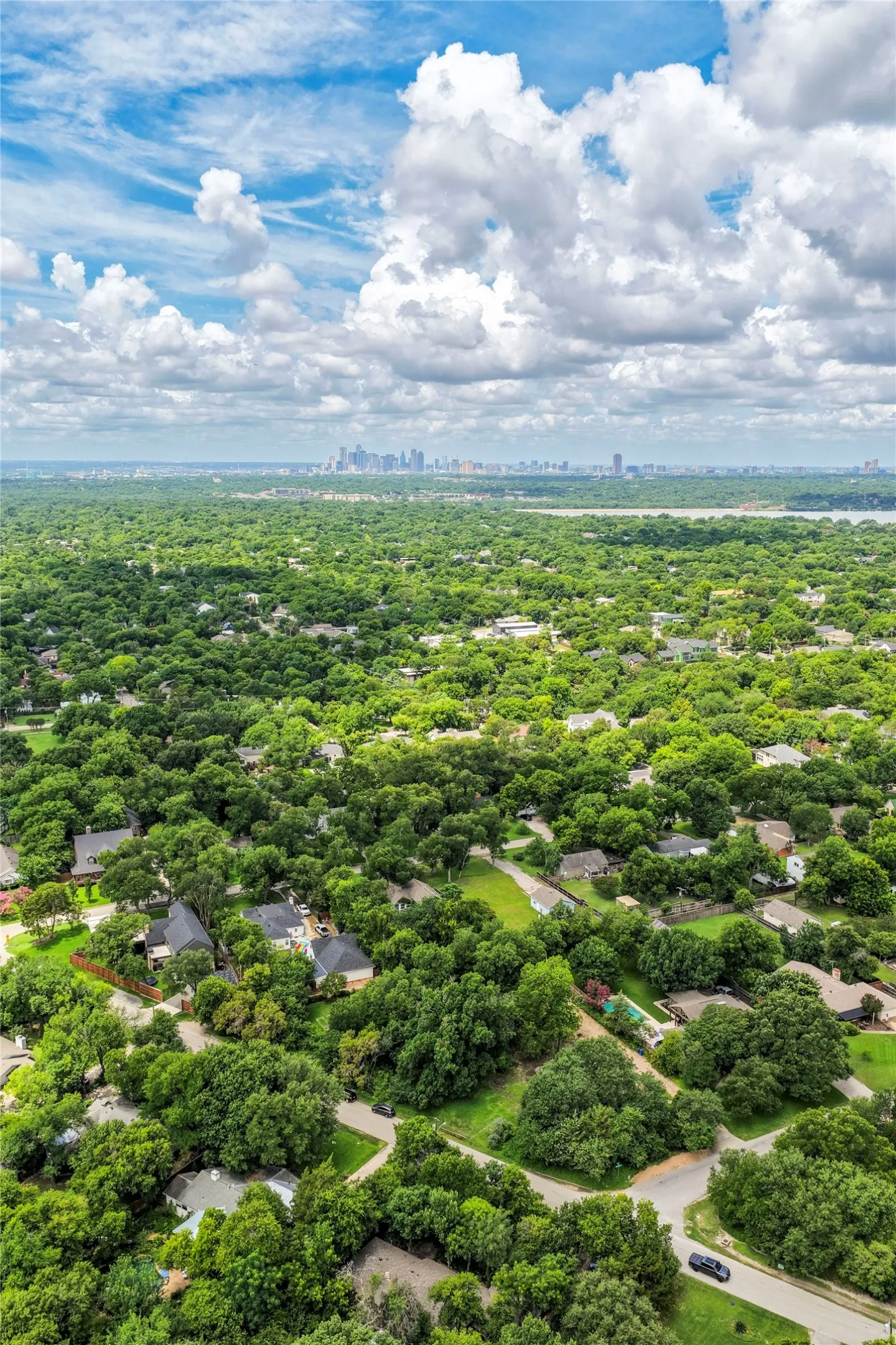 Expansive residential area with abundant mature trees and a distant cityscape