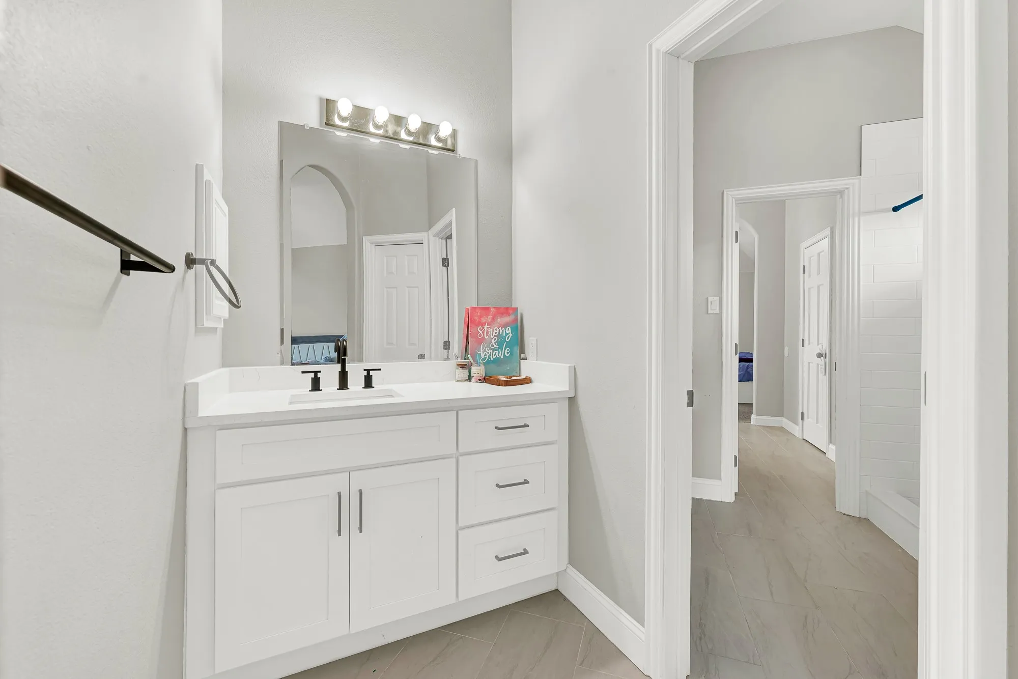 Bathroom vanity featuring a white countertop, undermount sink, and matte black faucet