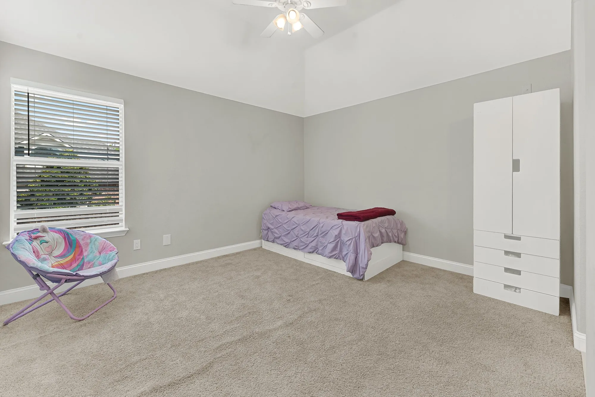 Spacious room featuring vaulted ceilings, light gray wall paint, and light-colored carpeting