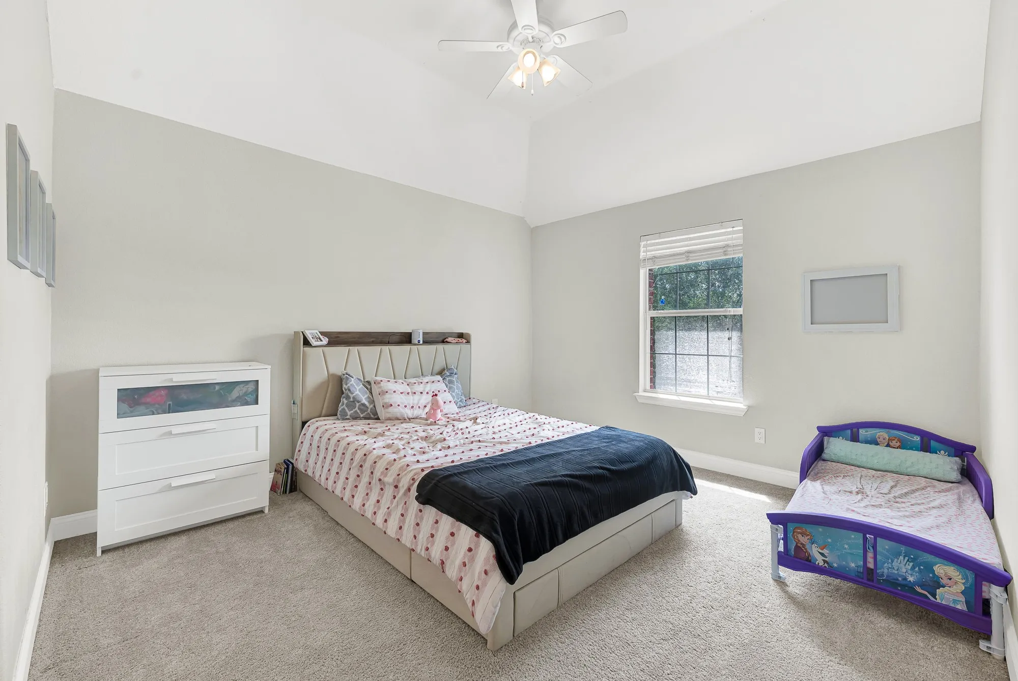 Vaulted ceiling bedroom featuring light gray wall paint, a ceiling fan, and carpeted flooring