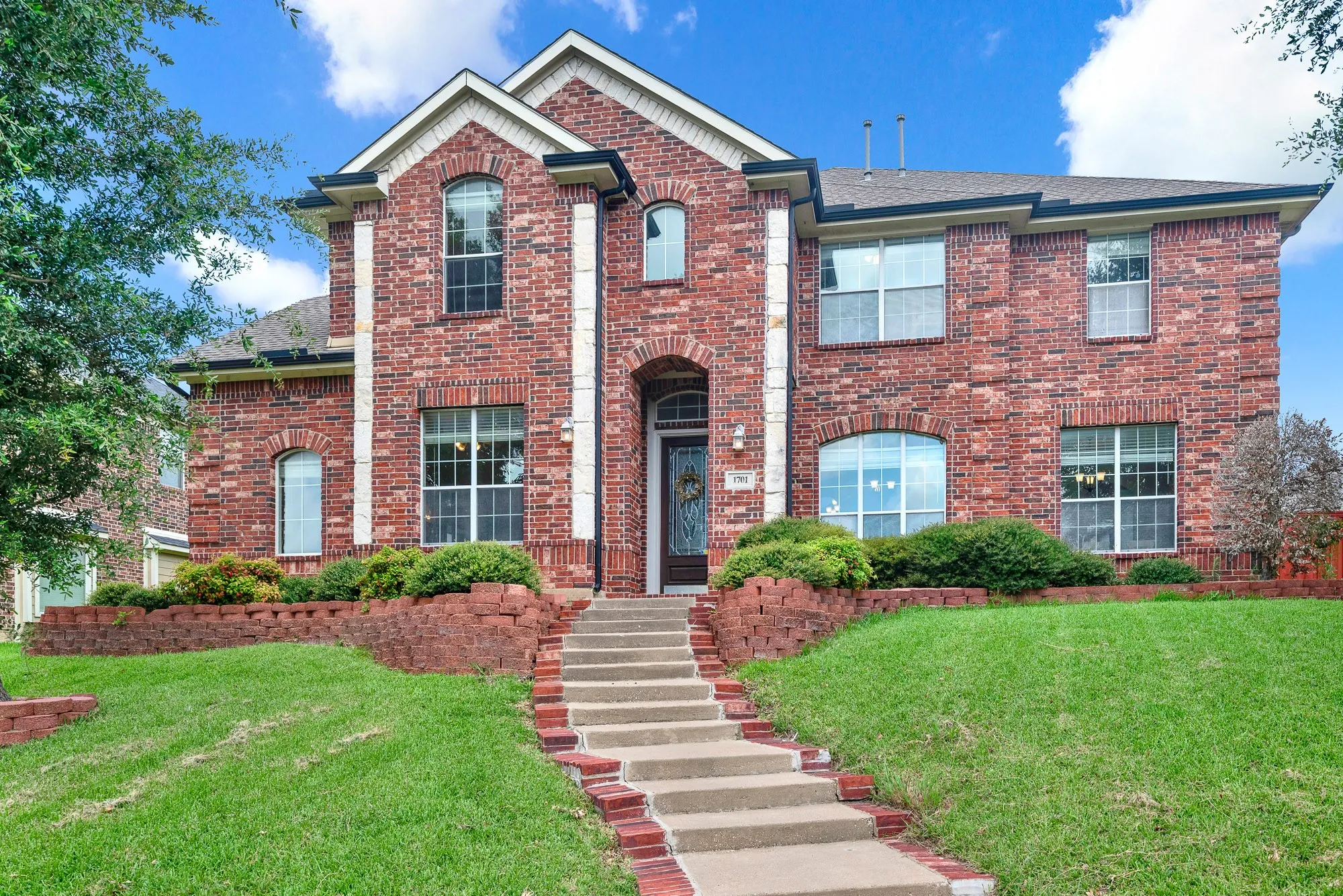 Brick facade residence featuring a prominent entry staircase with brick accents
