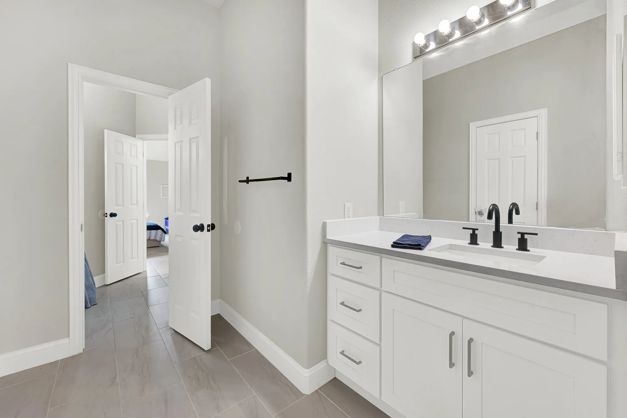 Bathroom vanity featuring a white countertop with integrated sink, matte black faucet, and white cabinetry with brushed nickel hardware