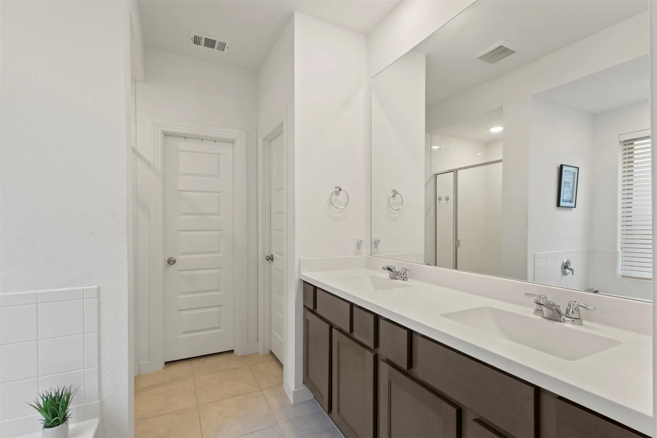 Full bathroom featuring a stall shower, double vanity, and light tile patterned flooring