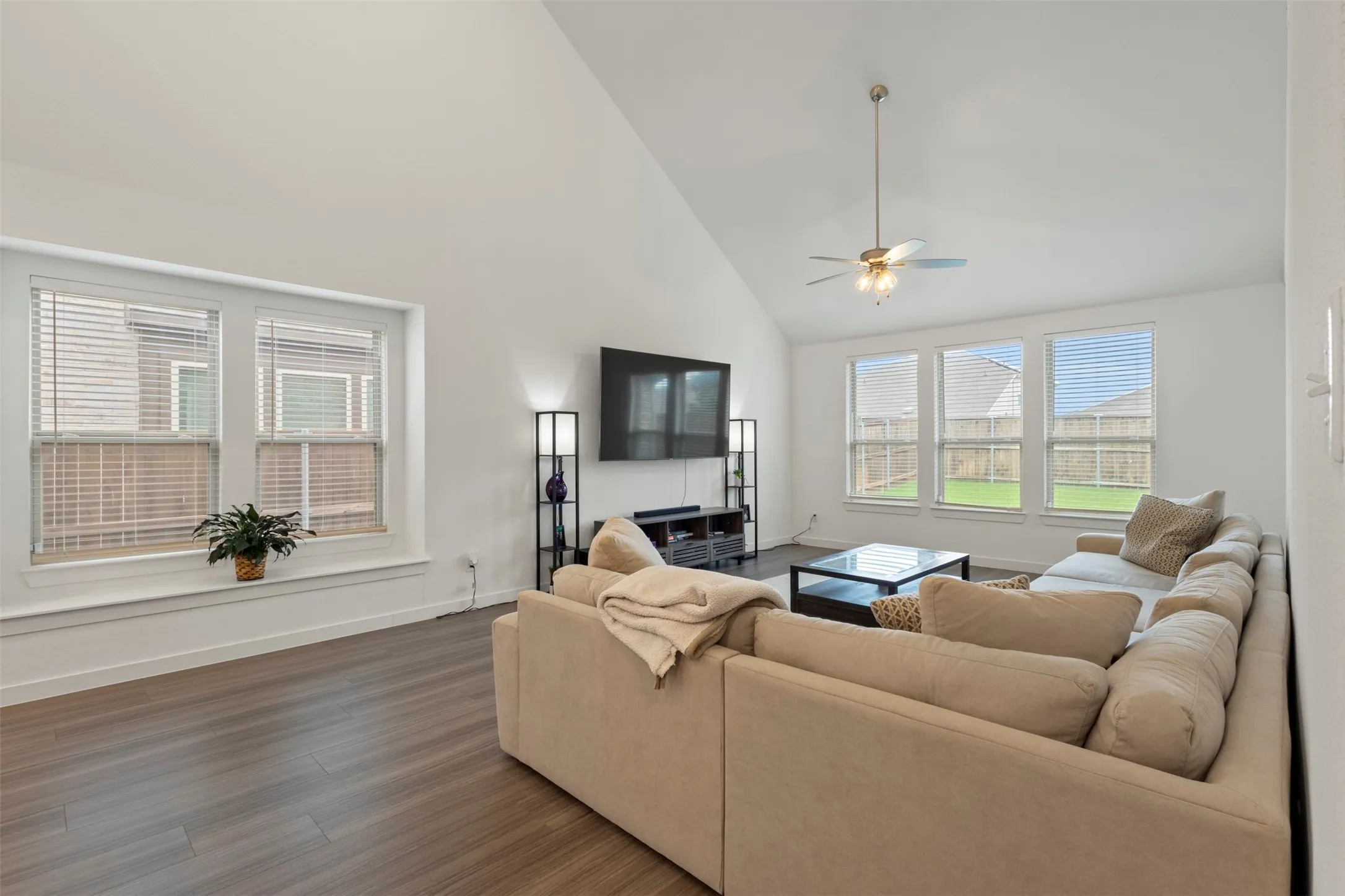Living room featuring high vaulted ceiling, wood-type flooring, and a ceiling fan