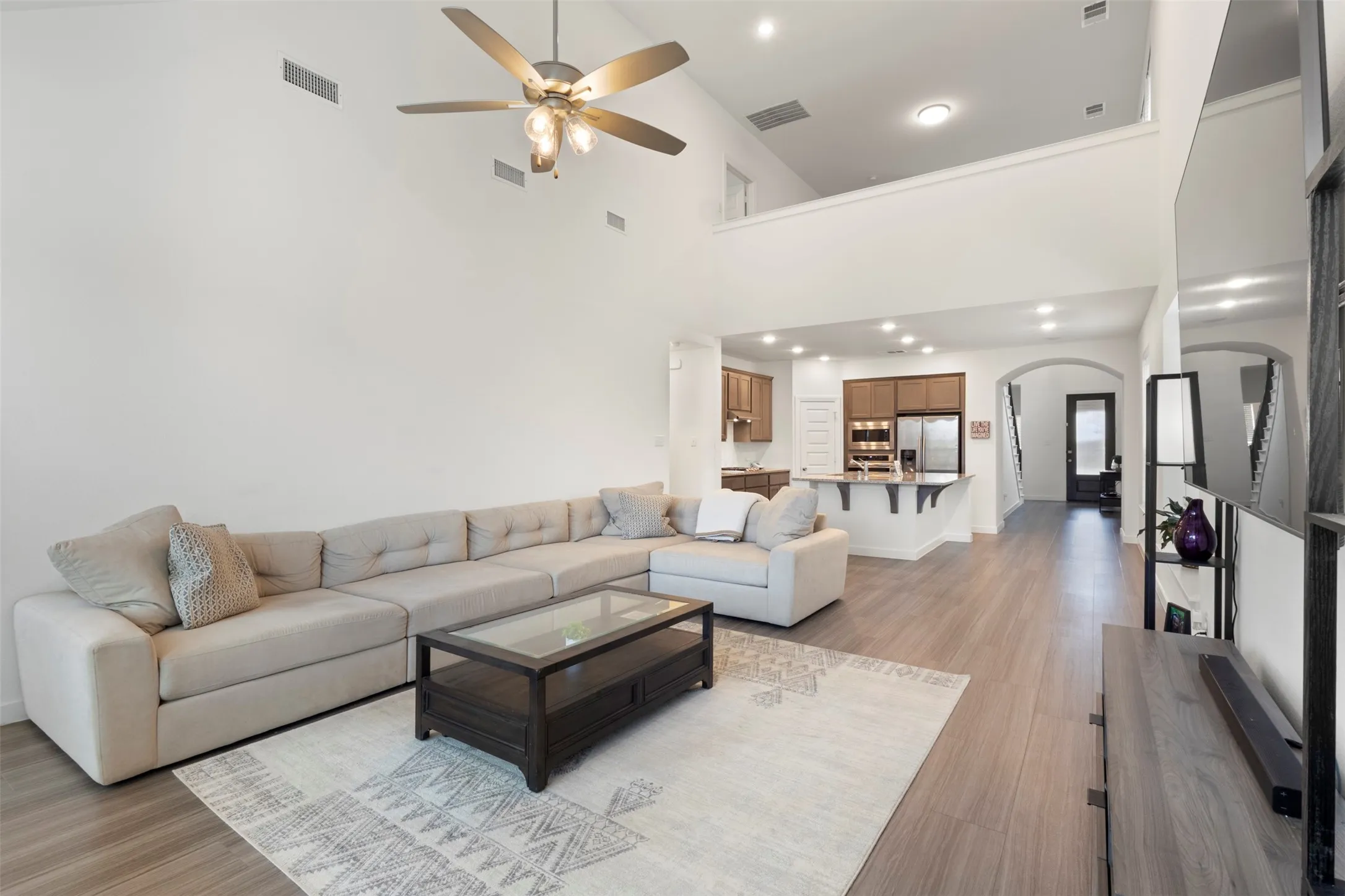 Living room with high vaulted ceiling, light wood-style flooring, and ceiling fan