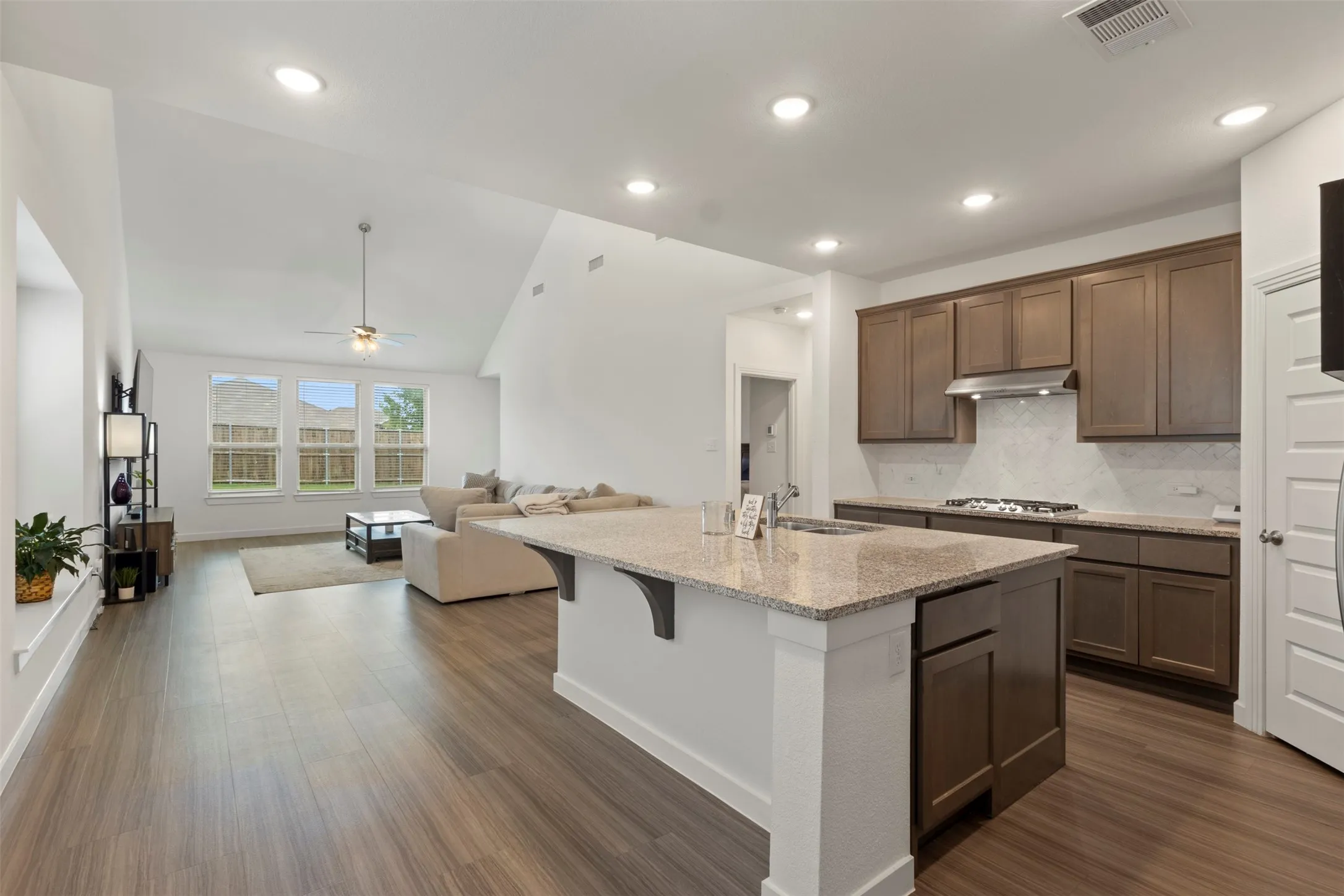 Kitchen with wood-style flooring, light stone countertops, tasteful backsplash, stainless steel appliances, and recessed lighting