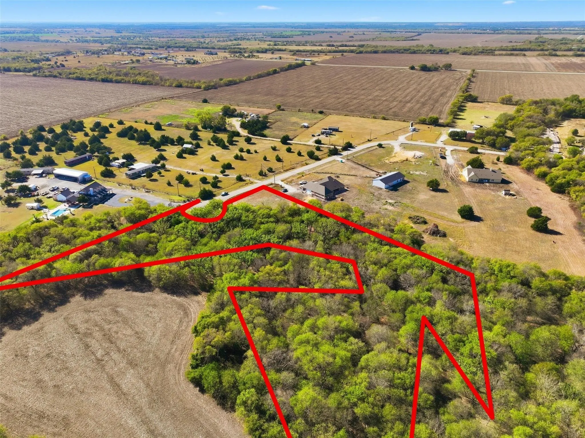 Expansive undeveloped parcel featuring mature trees, a clear boundary outline, and direct road frontage