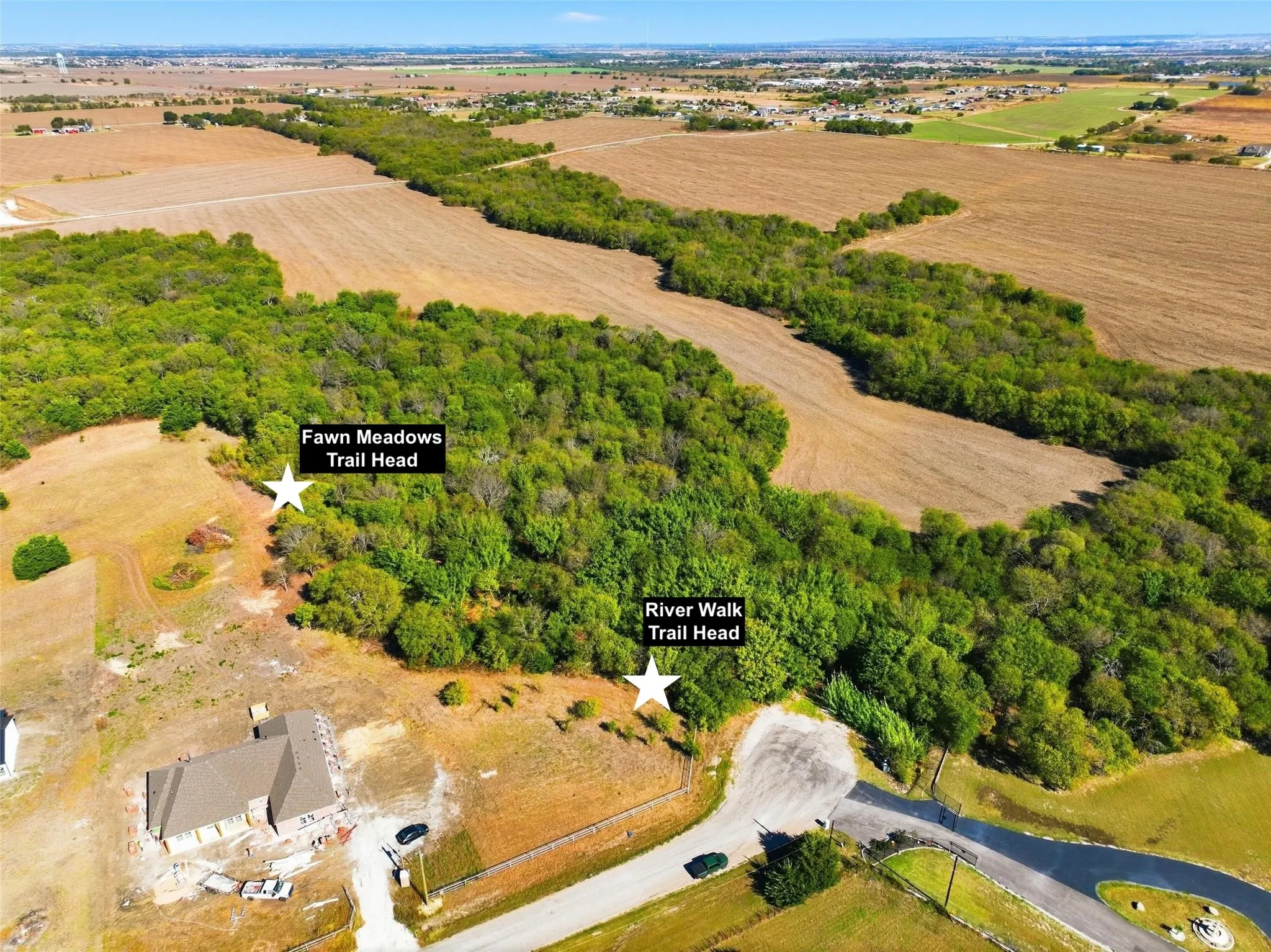 Expansive aerial perspective showcasing a residential development alongside cultivated fields and natural tree lines