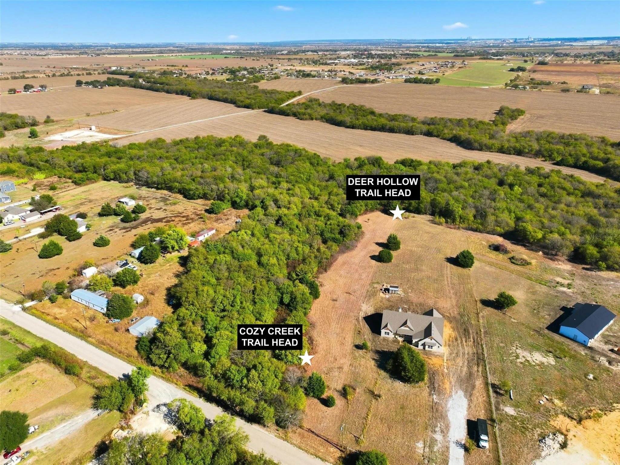 Expansive land parcel featuring wooded areas, a single-family residence, and a detached structure