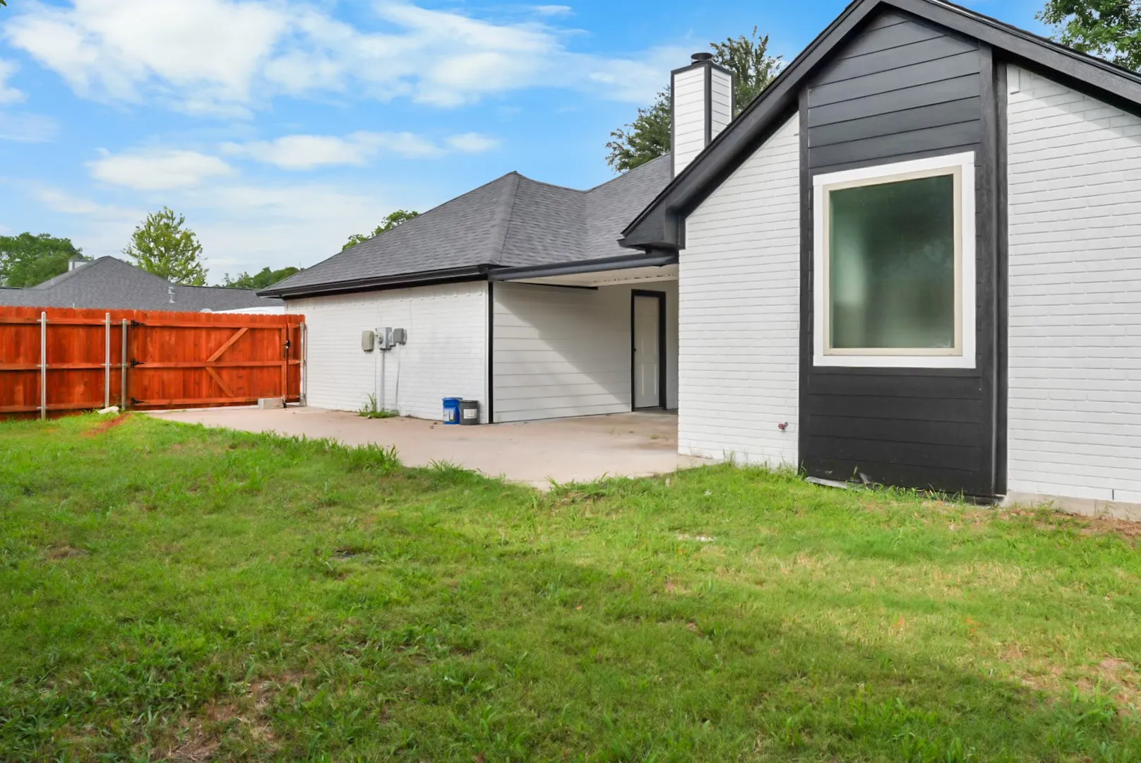 Side exterior featuring white painted brick and dark horizontal siding accents
