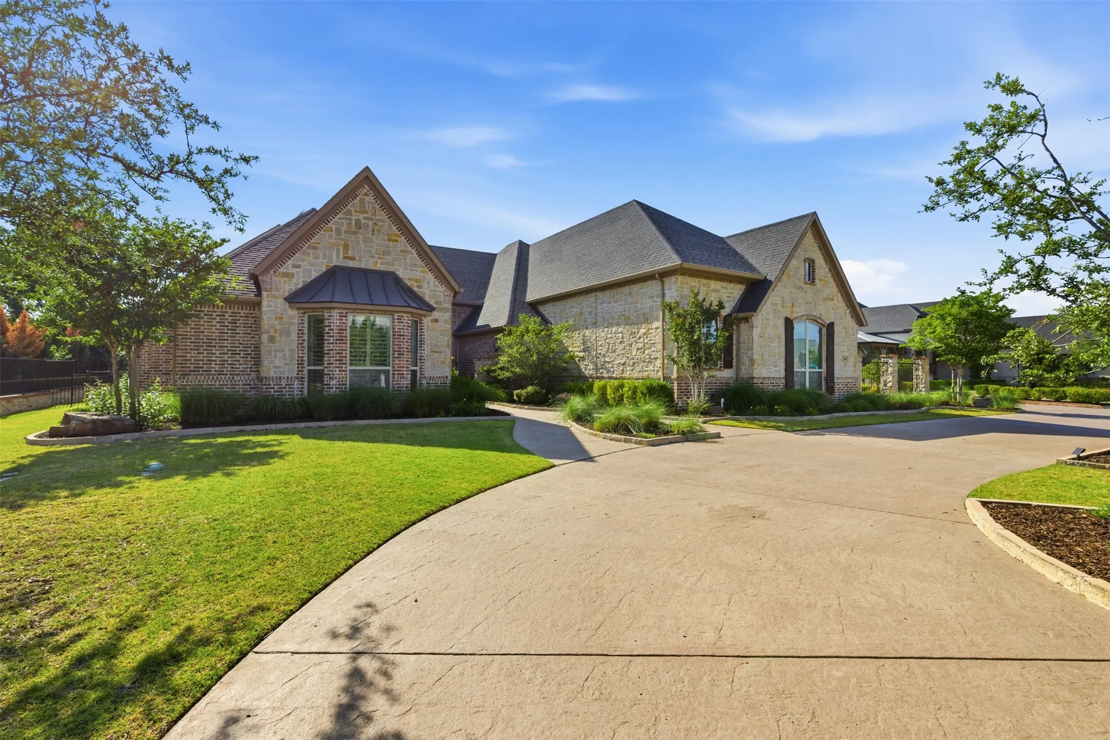Stone and brick exterior featuring multiple gables and a stamped concrete driveway