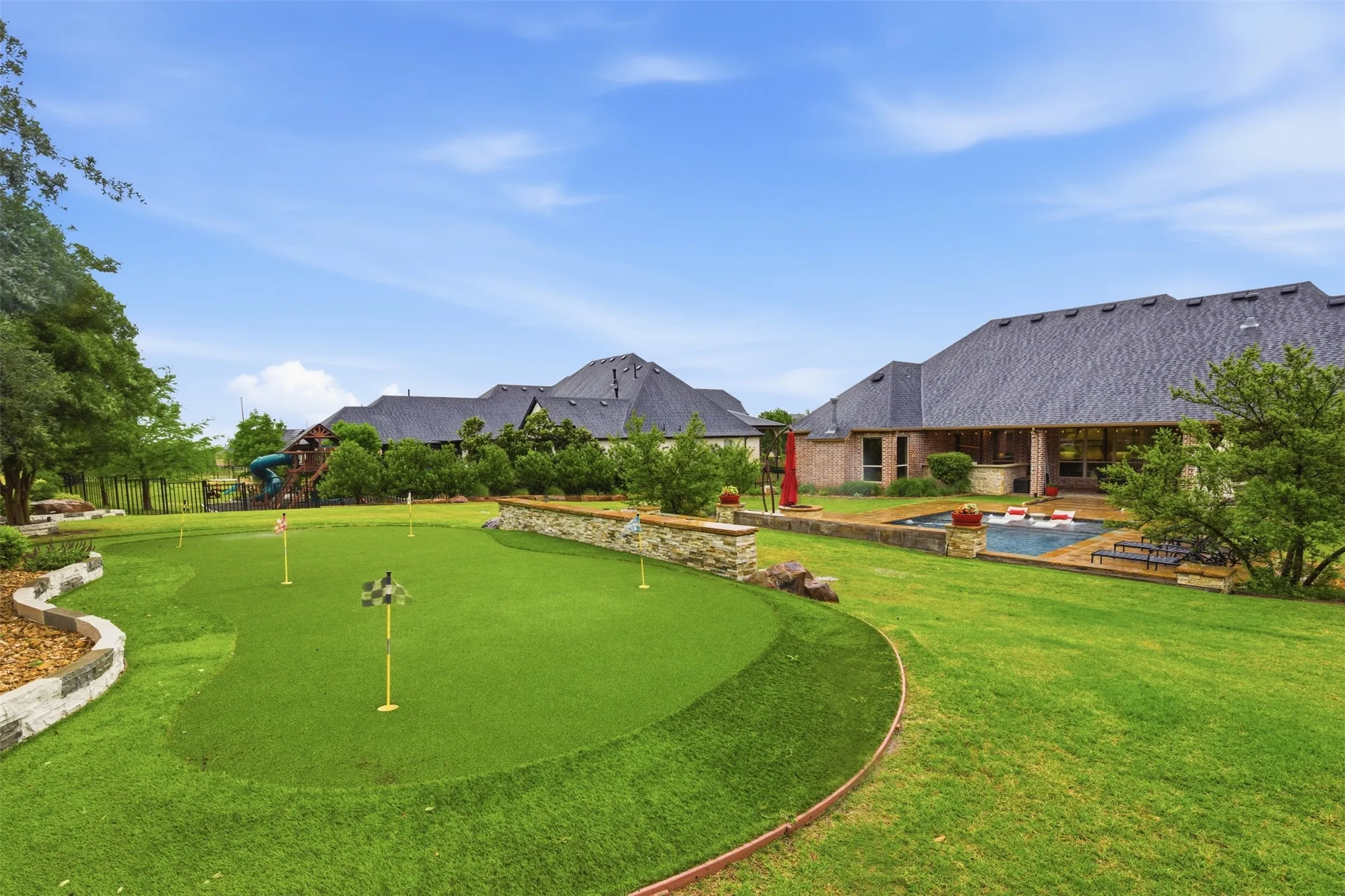 Expansive backyard featuring a putting green, a swimming pool, and a covered patio area