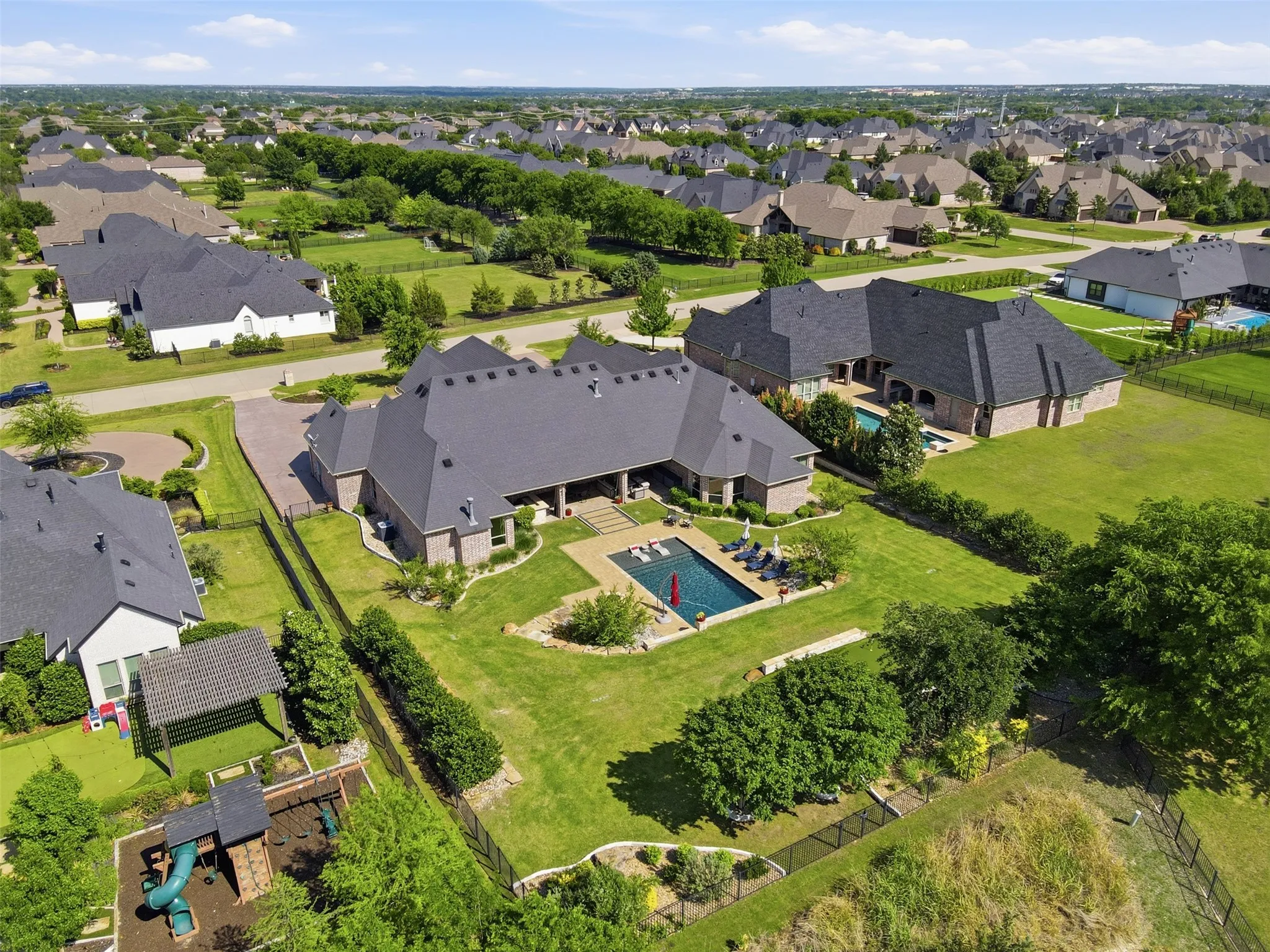 Expansive backyard featuring a rectangular swimming pool, integrated spa, surrounding paver patio, and lush green lawn