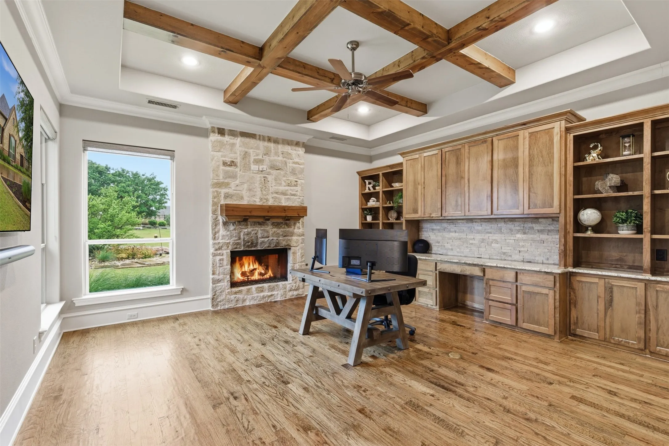 Spacious room featuring wood-finish flooring and a stone-clad fireplace with a wood mantle