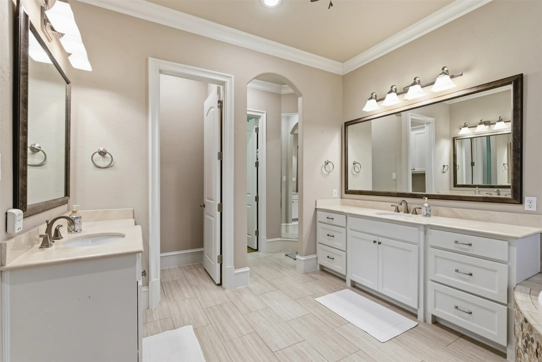 Dual vanity bathroom featuring light wood-finish tile flooring, white cabinetry, light-toned countertops, and brushed nickel hardware