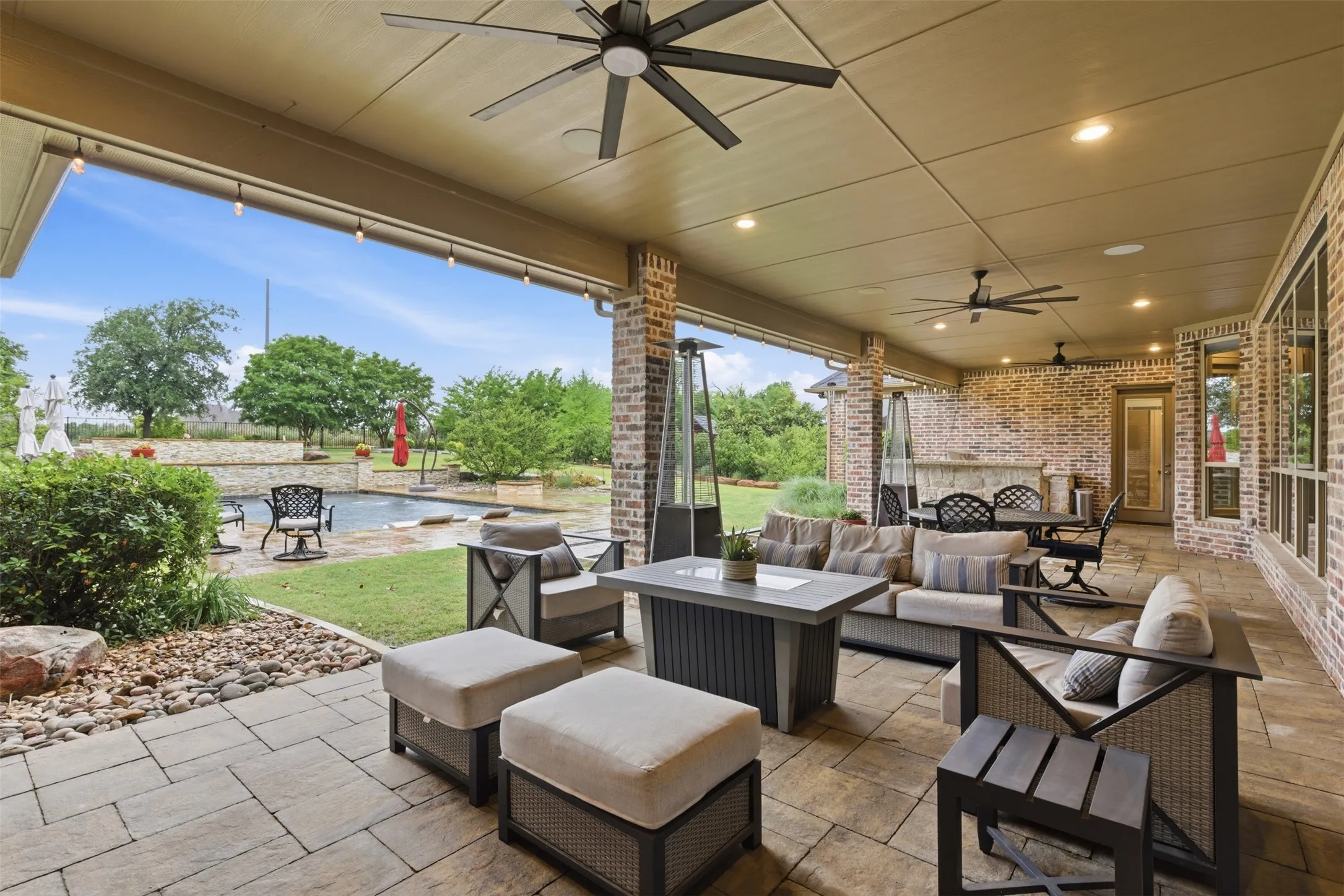 Covered patio featuring brick columns and walls, an integrated outdoor kitchen, and recessed lighting
