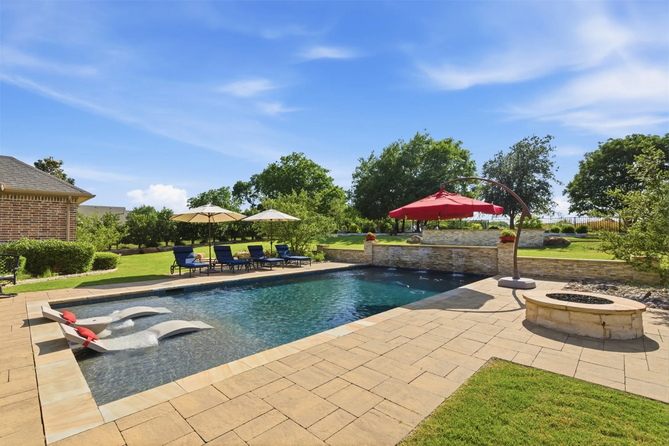 Rectangular swimming pool with integrated tanning ledge and natural stone paver surround