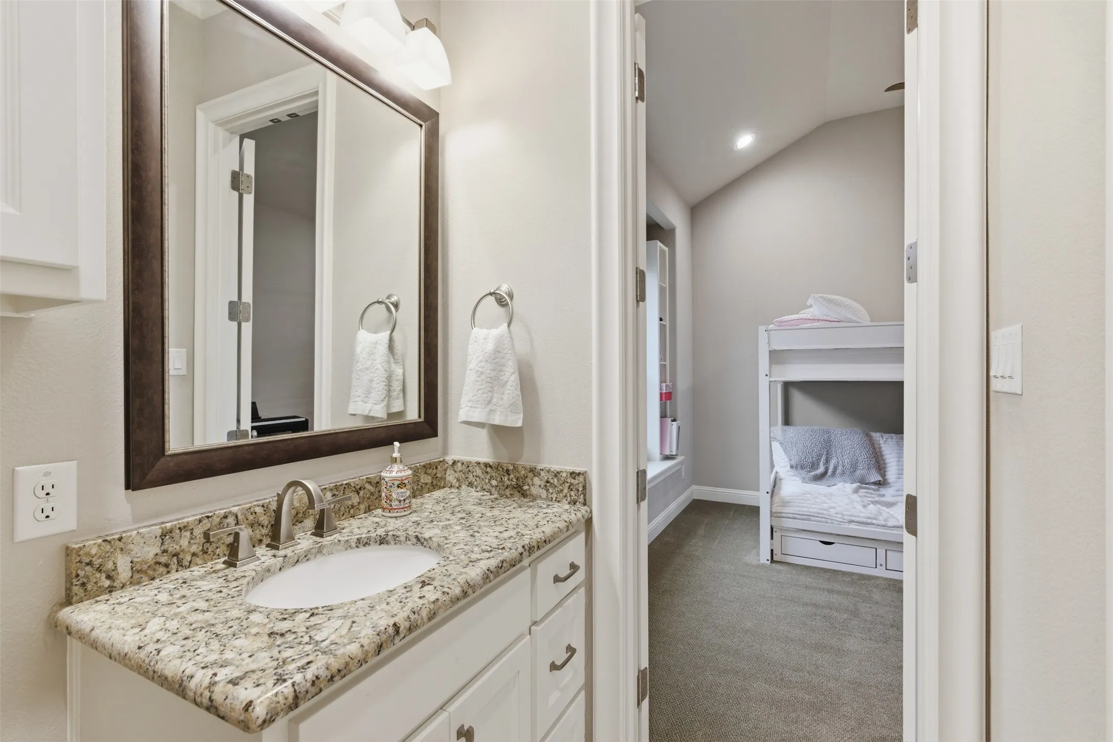Bathroom vanity with a speckled countertop, undermount sink, and brushed nickel faucet