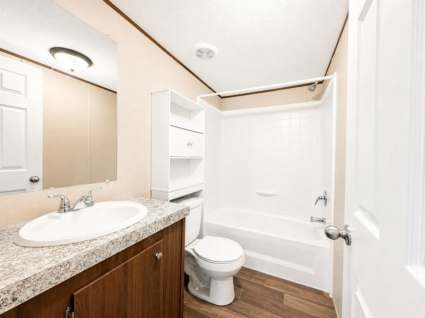 Bathroom featuring a wood-finish vanity with a speckled countertop, an integrated sink, and a built-in shower/tub combination