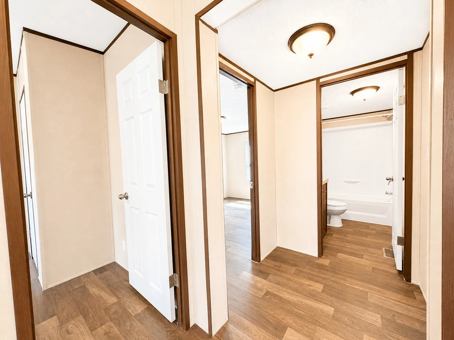 Hallway featuring wood-finish flooring, white paneled doors, and ceiling-mounted light fixtures
