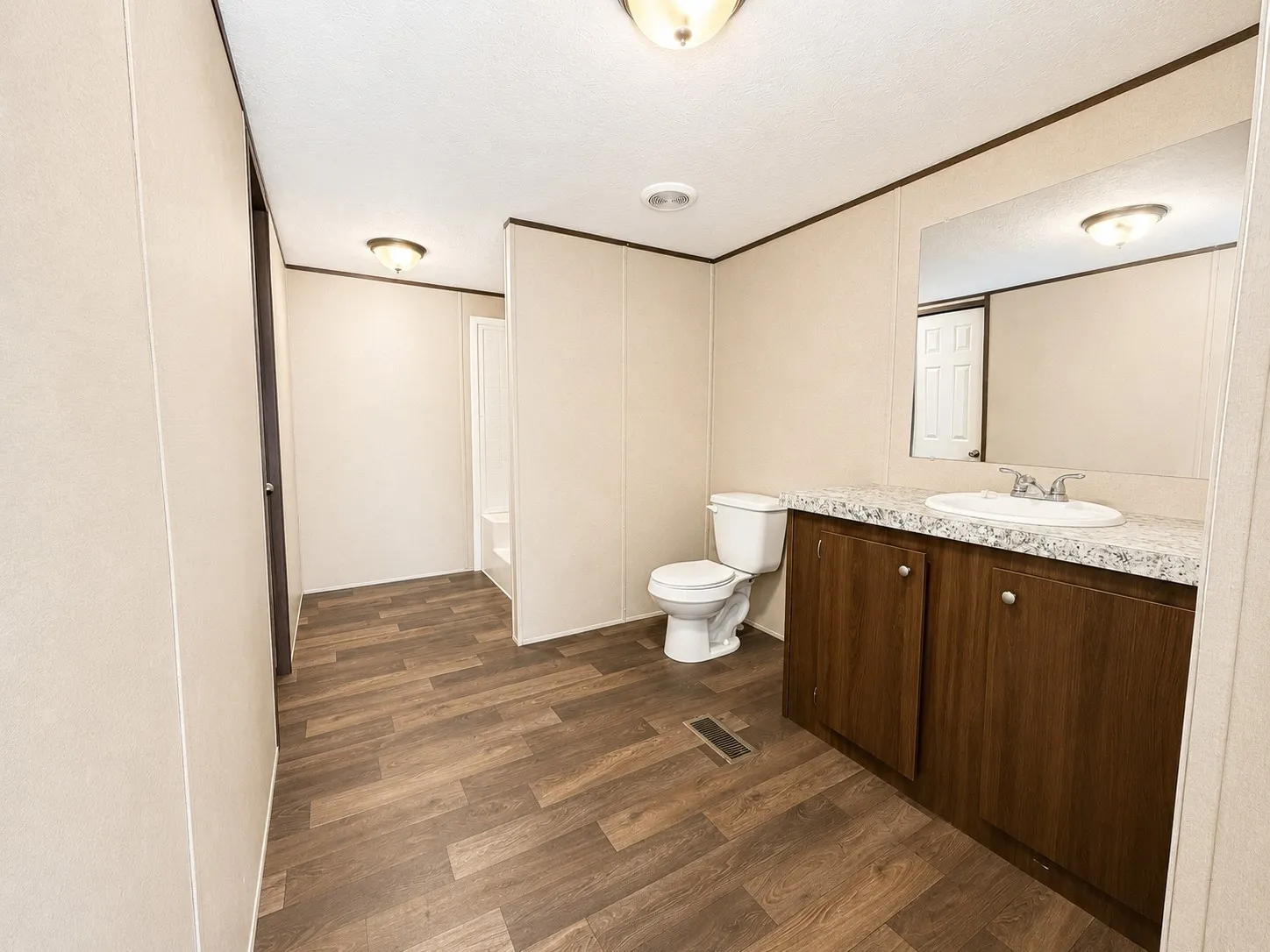 Hallway featuring wood-finish flooring, white paneled doors, and ceiling-mounted light fixtures