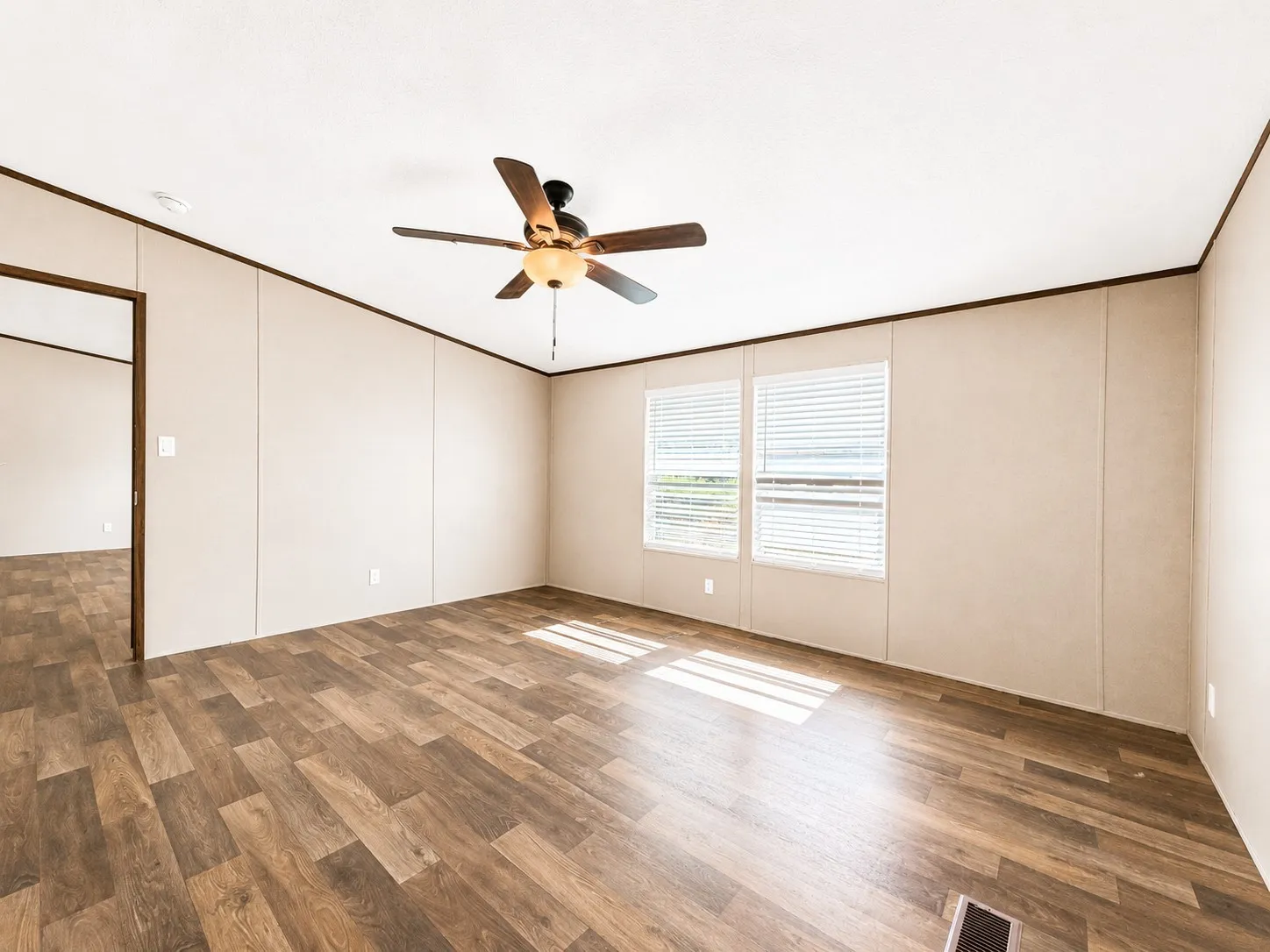 Room featuring wood-finish flooring, two window openings with horizontal blinds, and a ceiling fan with integrated lighting
