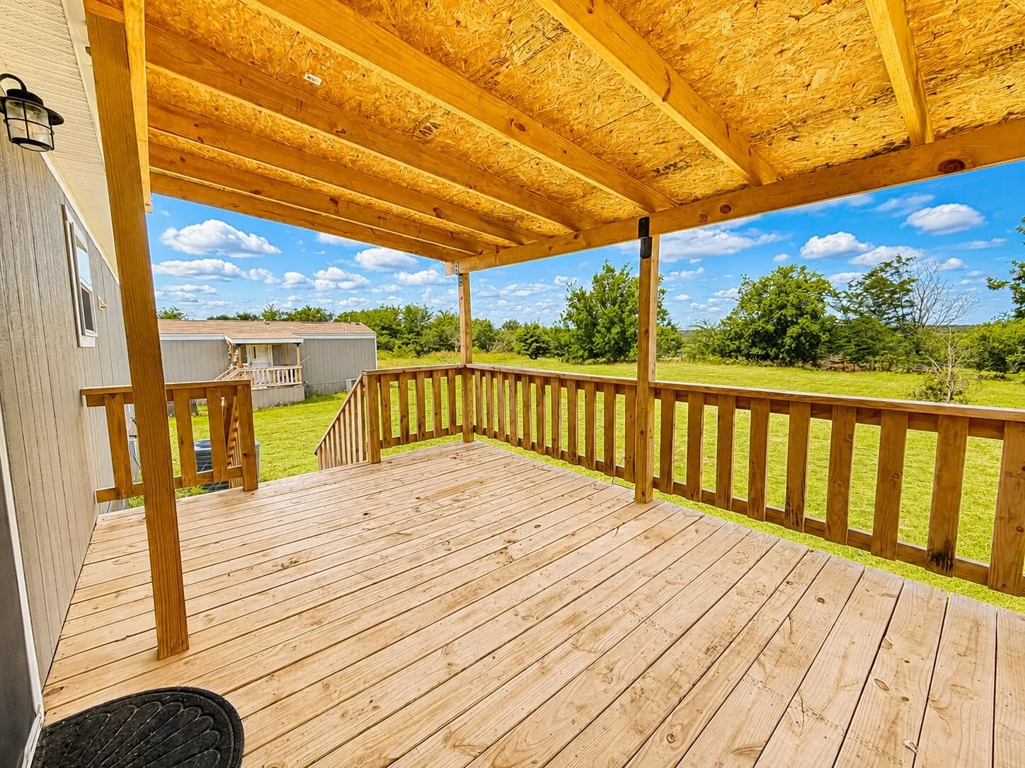 Expansive outdoor deck featuring wood flooring, wood railings, and a wood beam supported roof structure