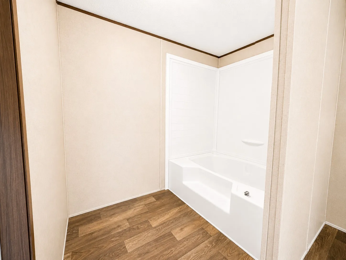 Enclosed bathtub with integrated shelving, surrounded by white wall panels