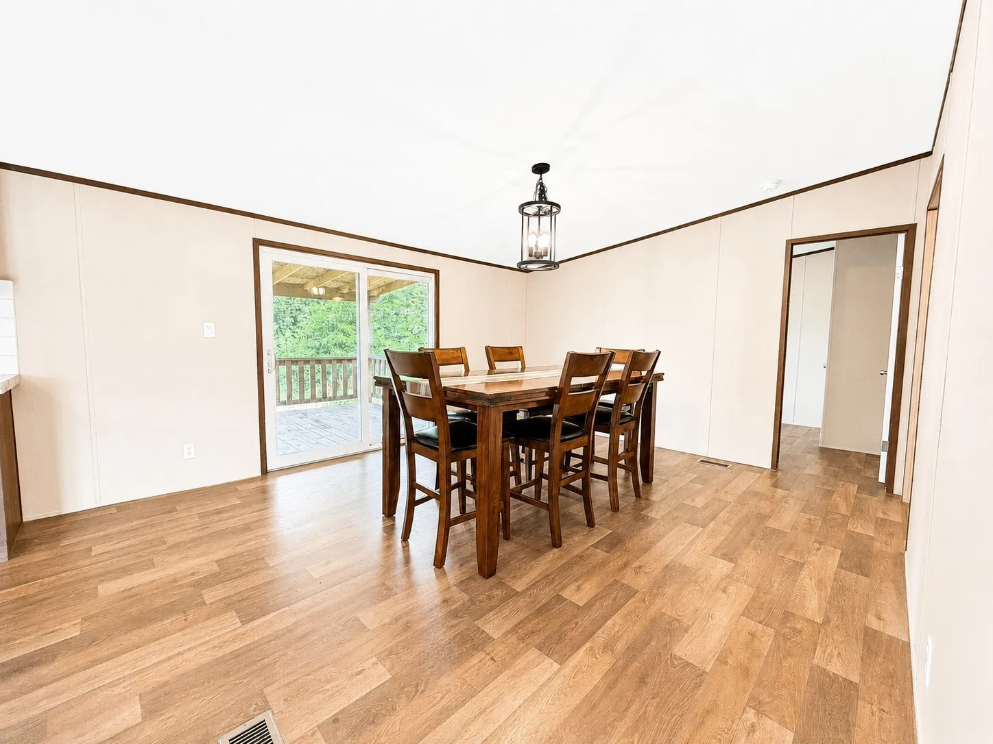 Dining area featuring wood-finish flooring, a contemporary ceiling light fixture, and a sliding glass door leading to an outdoor deck