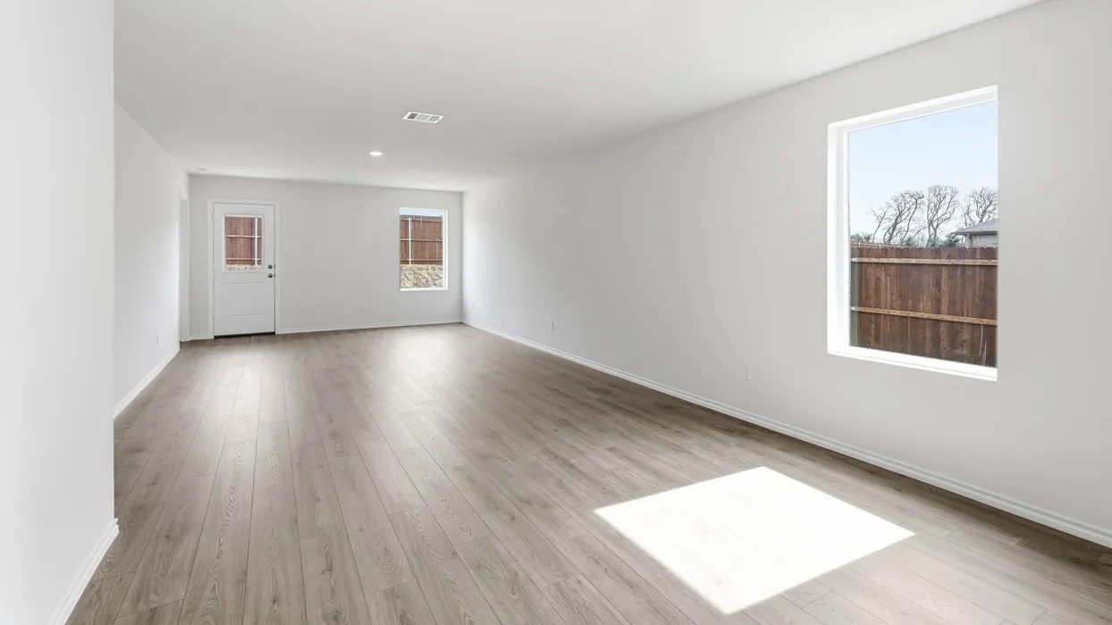 Spacious room featuring wood-finish flooring, white walls, and multiple windows