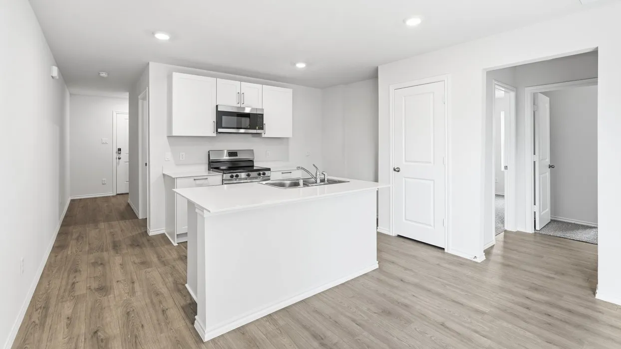Kitchen island with white cabinetry, stainless steel appliances, and wood-finish flooring