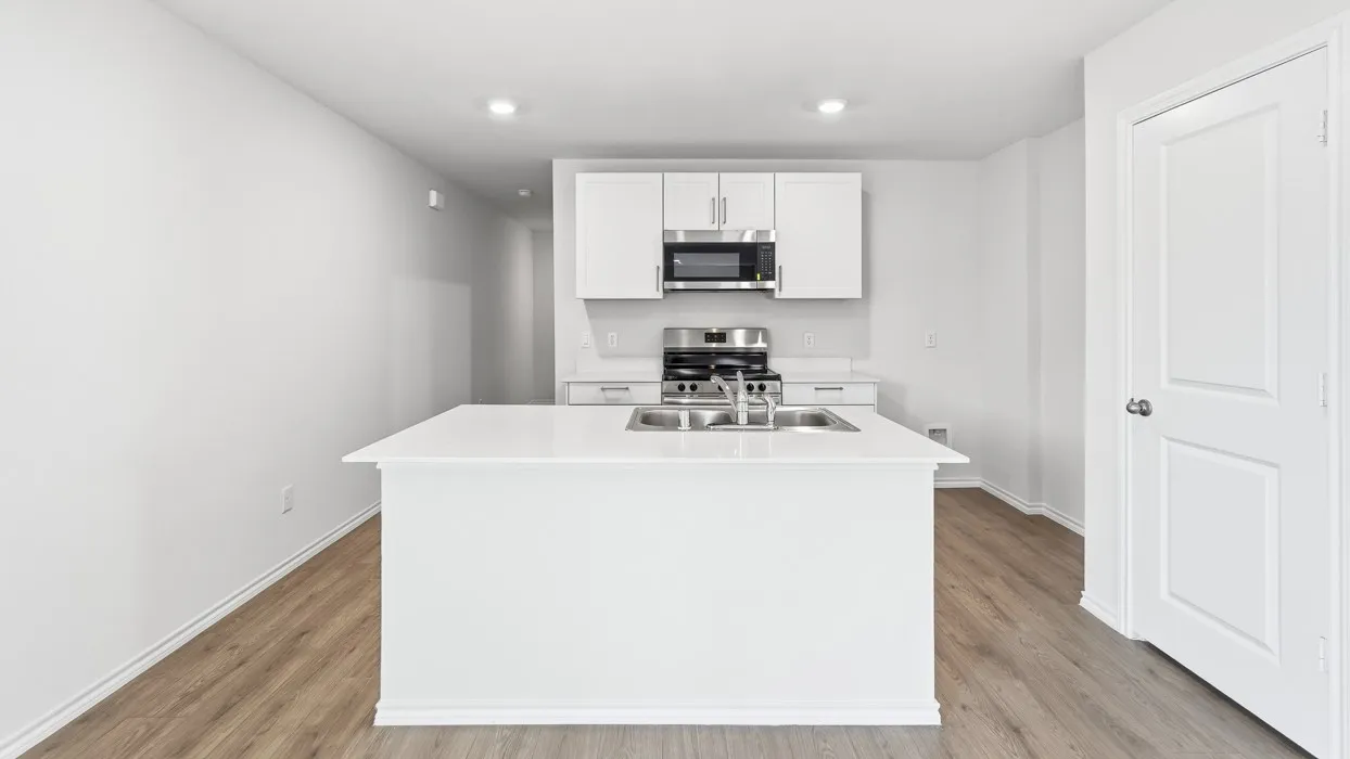 Modern kitchen featuring a white island with an undermount double basin sink and a stainless steel faucet
