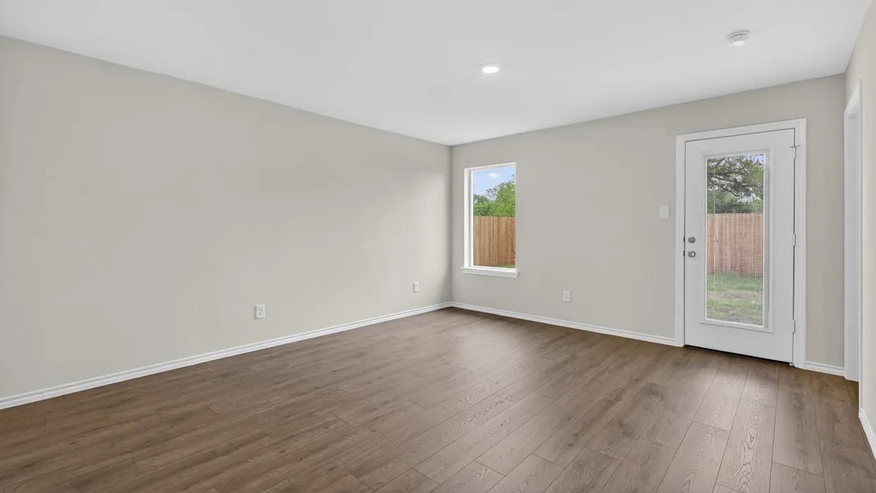 Spacious interior room featuring wood-finish flooring, light-toned walls, recessed ceiling lighting, a single window, and a glass-paneled exterior door