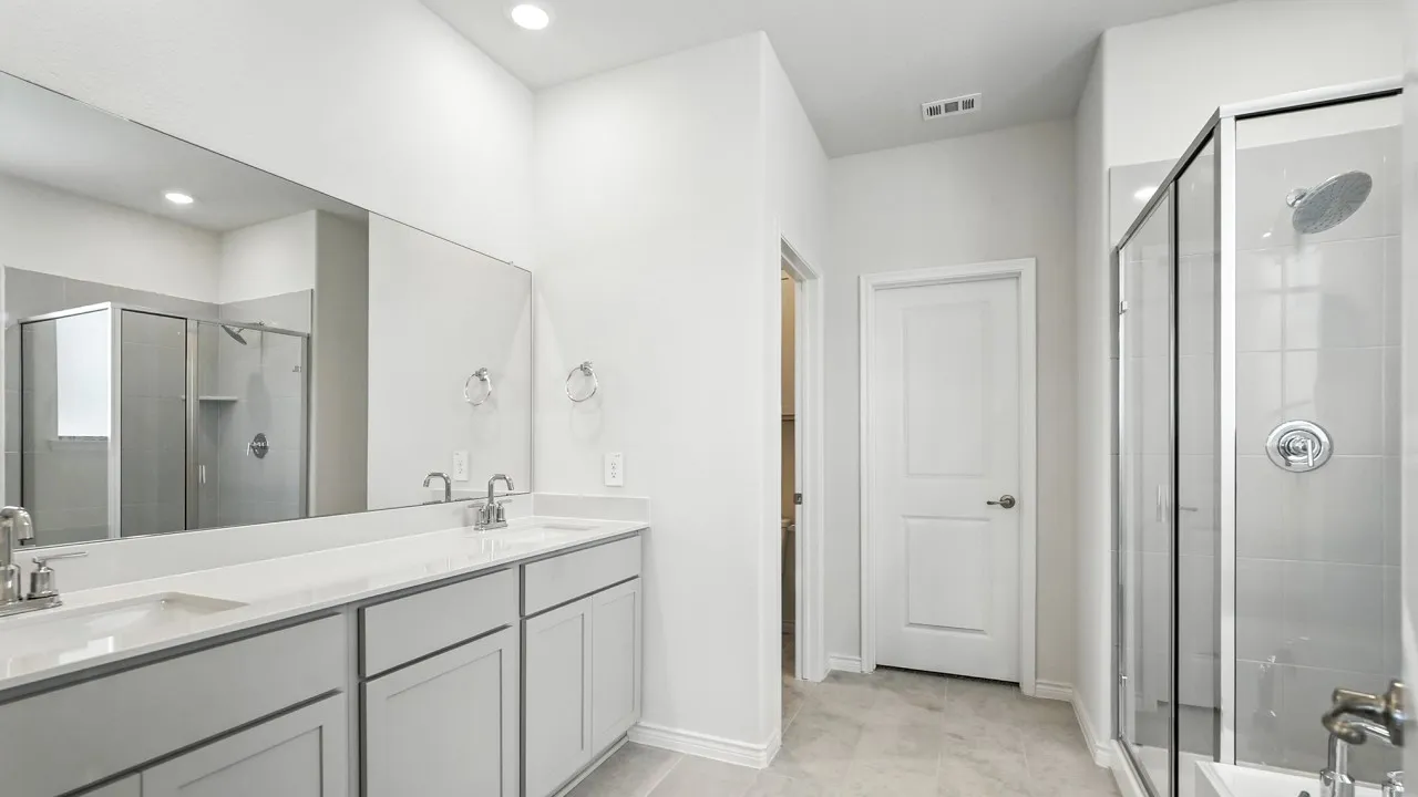 Contemporary bathroom featuring a double vanity with light gray cabinetry, a spacious framed glass shower, and large format floor tiling