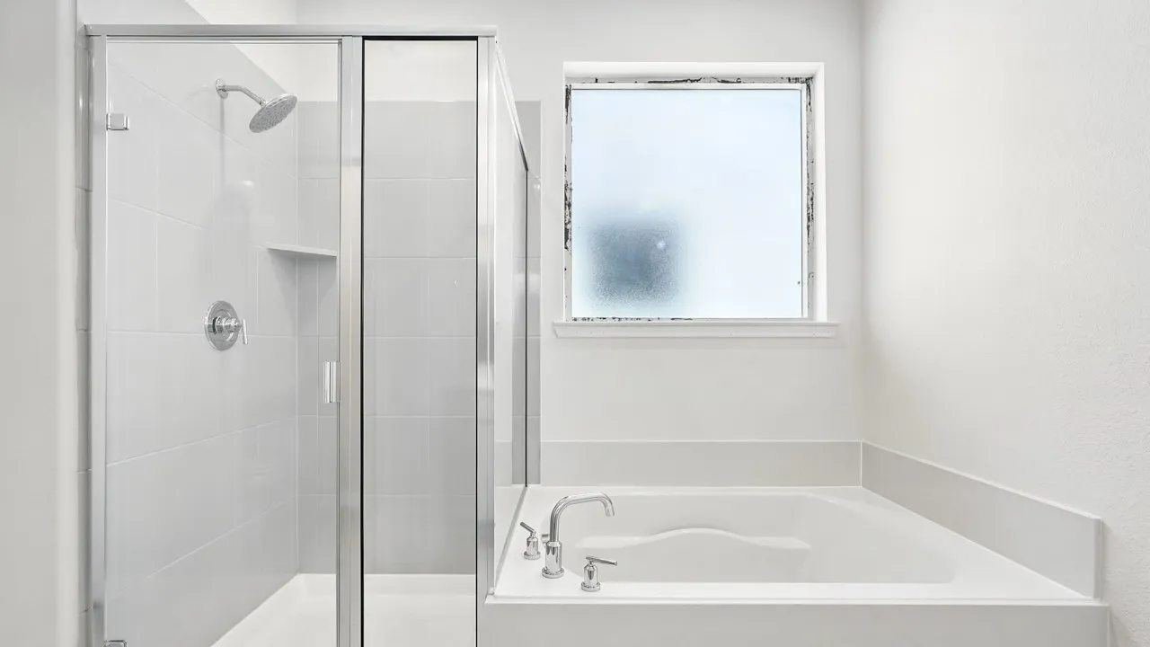 Bathroom featuring a built-in soaking tub with deck-mounted fixtures, a glass-enclosed shower with tile surround and niche, a frosted window, and clean white walls