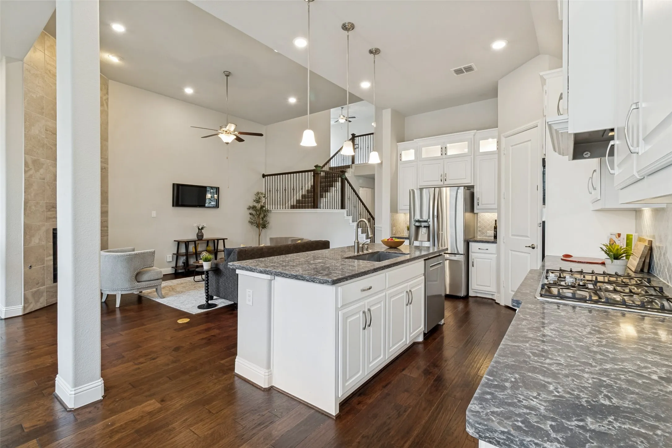 Open-concept kitchen featuring white cabinetry, stone-finish countertops, stainless steel appliances, and a gas cooktop
