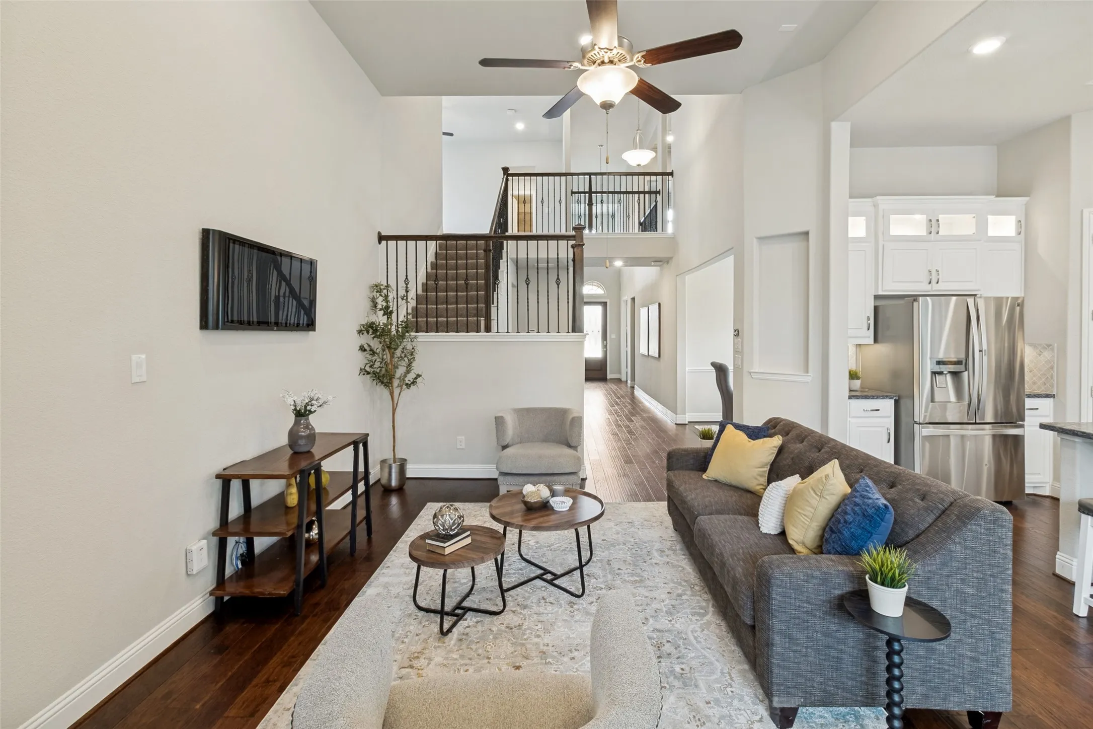 Vaulted living area featuring wood-finish flooring, a ceiling fan with integrated lighting, and direct access to the kitchen