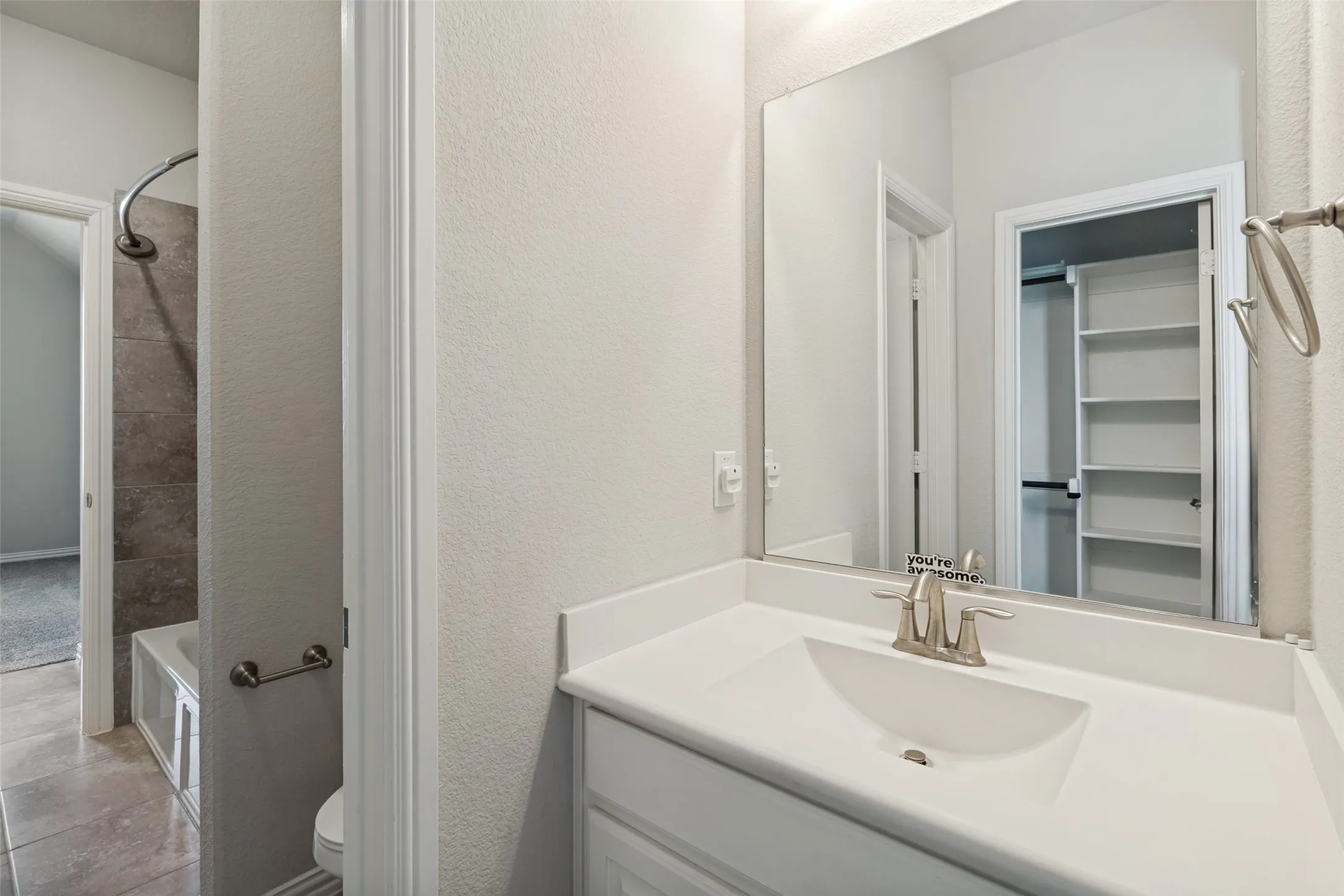 Bathroom featuring an integrated sink vanity with brushed nickel fixtures, a full-width mirror, tile flooring, and a tub with a tile surround