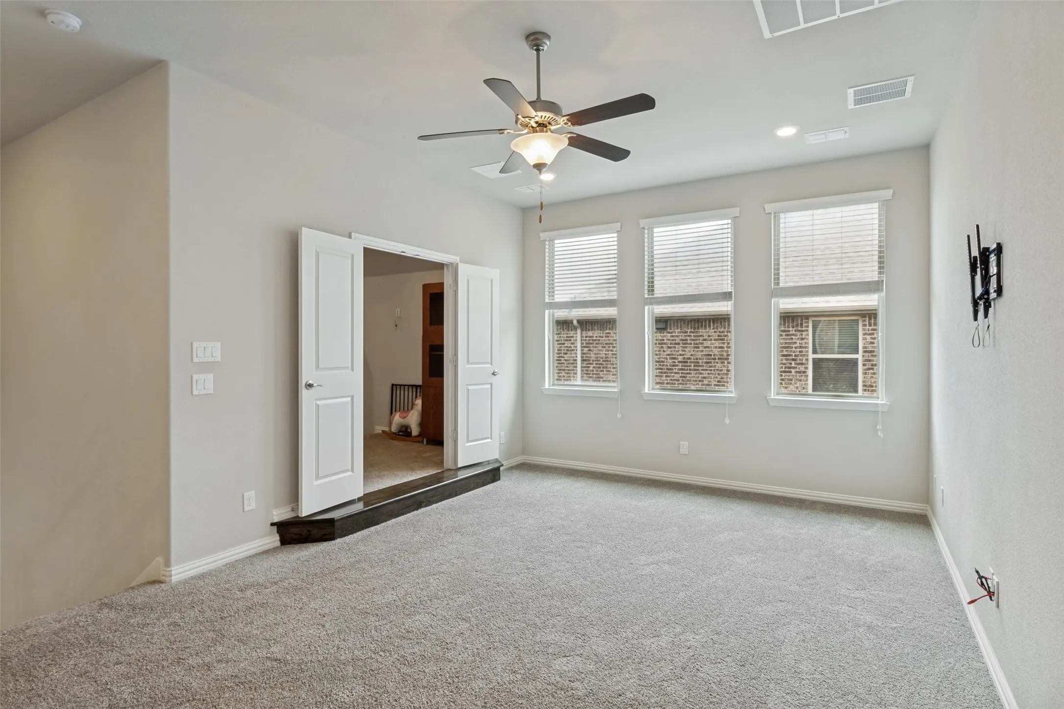 Open room featuring gray carpeting and three large windows with blinds
