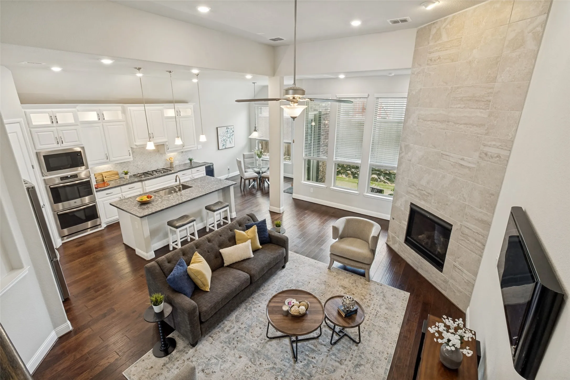 Expansive living area featuring soaring ceilings, wood-finish flooring, and a stone-clad fireplace