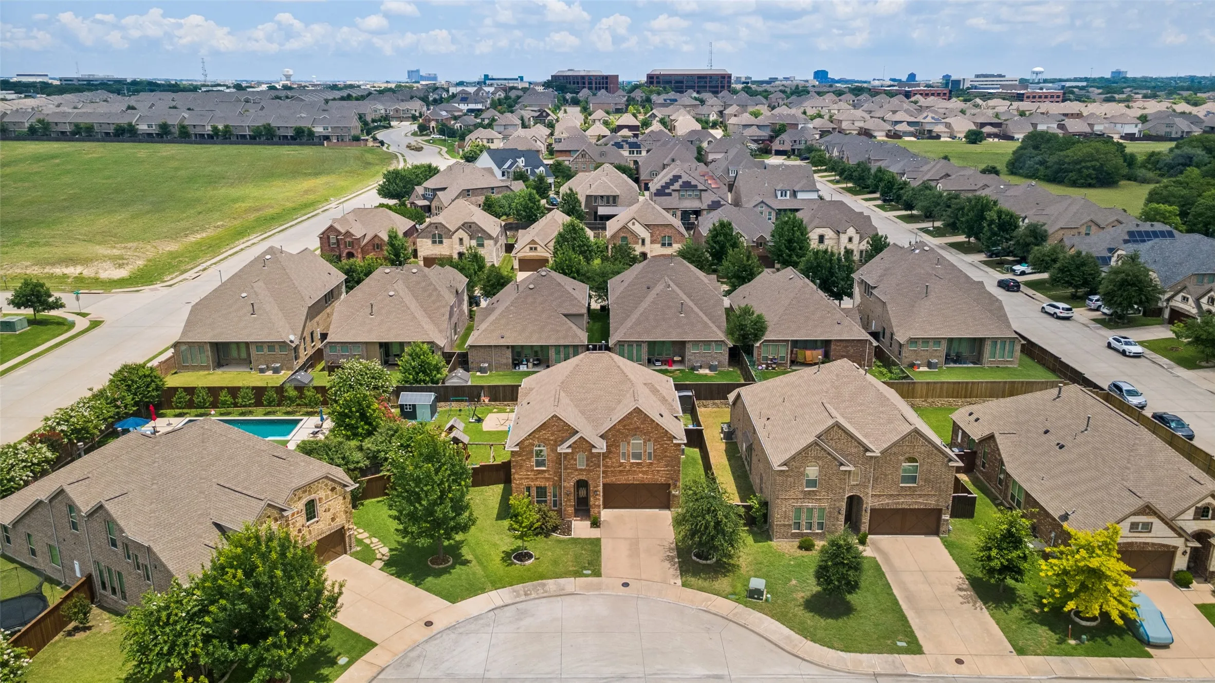 Aerial perspective showcasing a residential street with multiple properties, mature trees, and manicured lawns