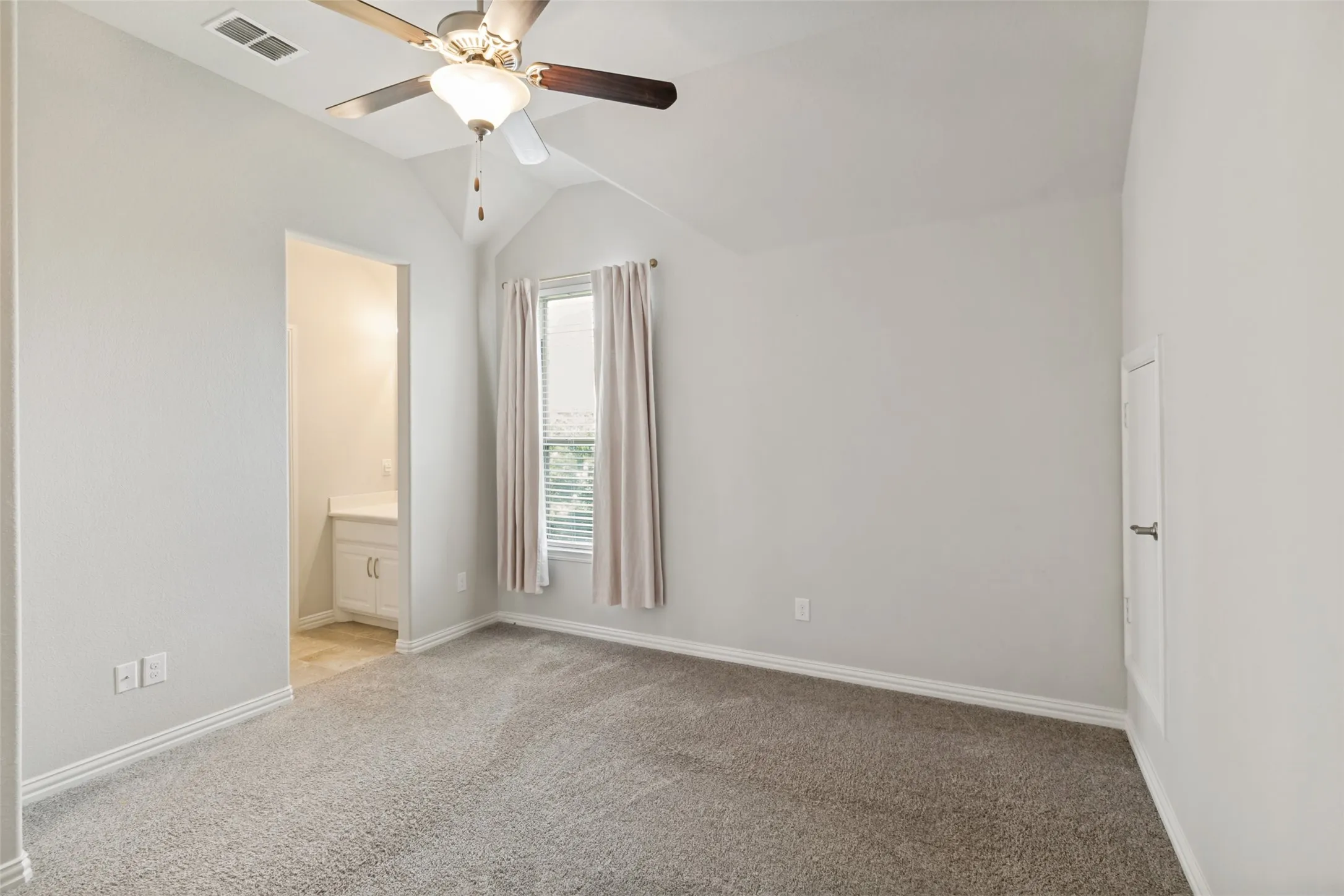 Carpeted room featuring a vaulted ceiling and a ceiling fan with integrated lighting