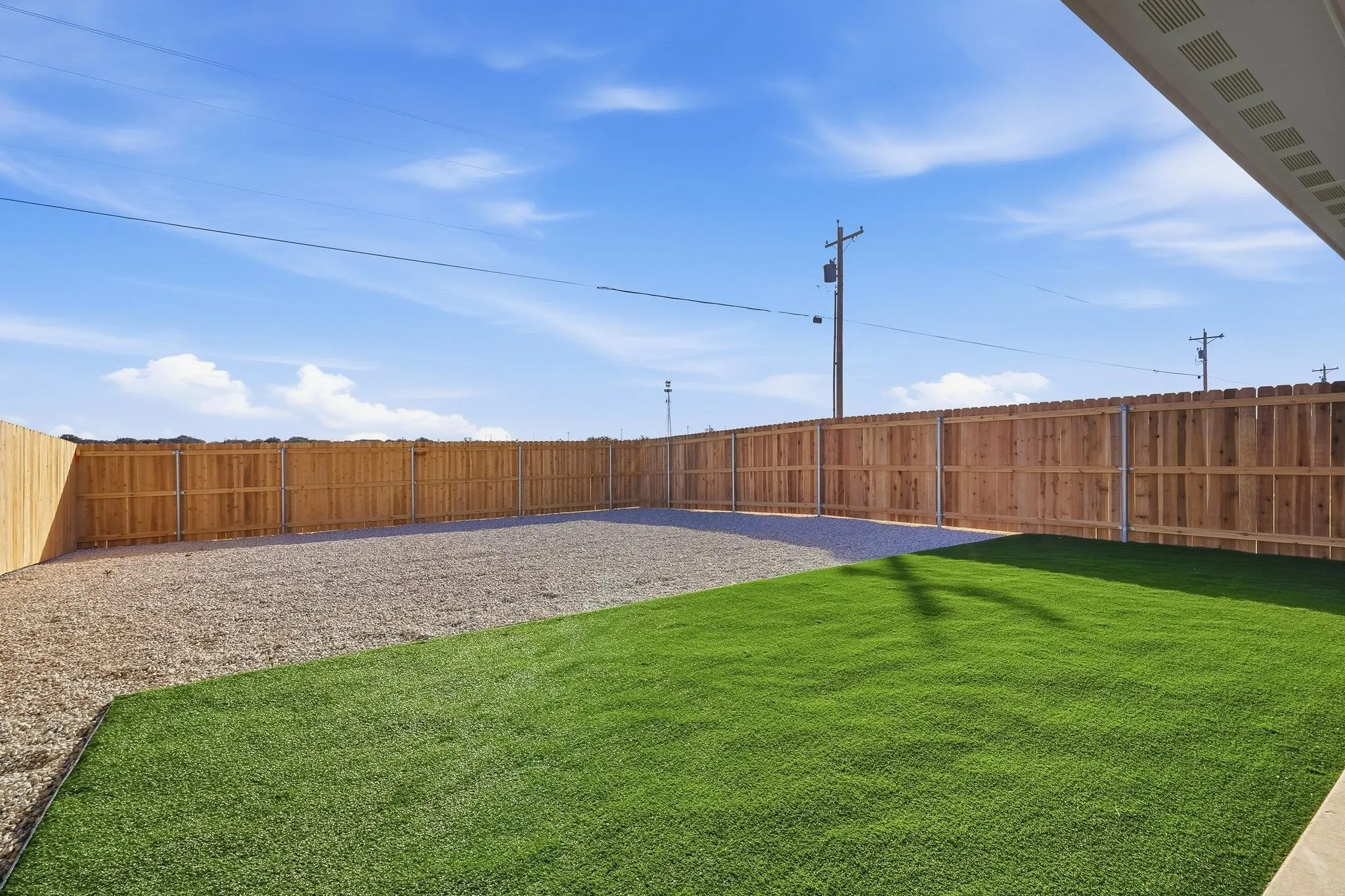 Private rear yard with artificial turf and gravel landscaping