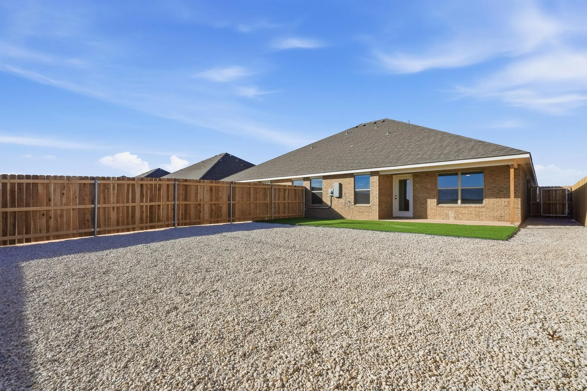 Rear exterior featuring a brick facade, pitched shingle roof, and multiple windows