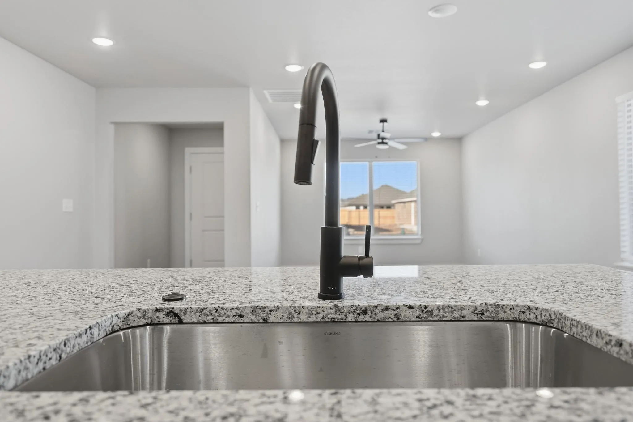 Kitchen island featuring a stainless steel undermount sink, a matte black gooseneck faucet, and a speckled granite countertop