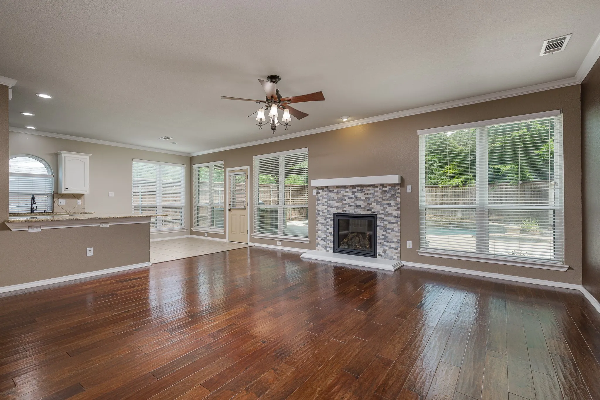 Spacious living area featuring rich wood-finish flooring, a contemporary tiled fireplace, and ample natural light from multiple windows