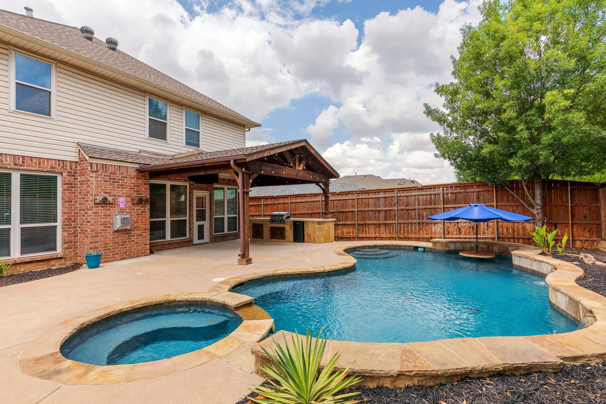 Backyard oasis featuring a free-form swimming pool with integrated spa, stone coping, and a rock waterfall feature